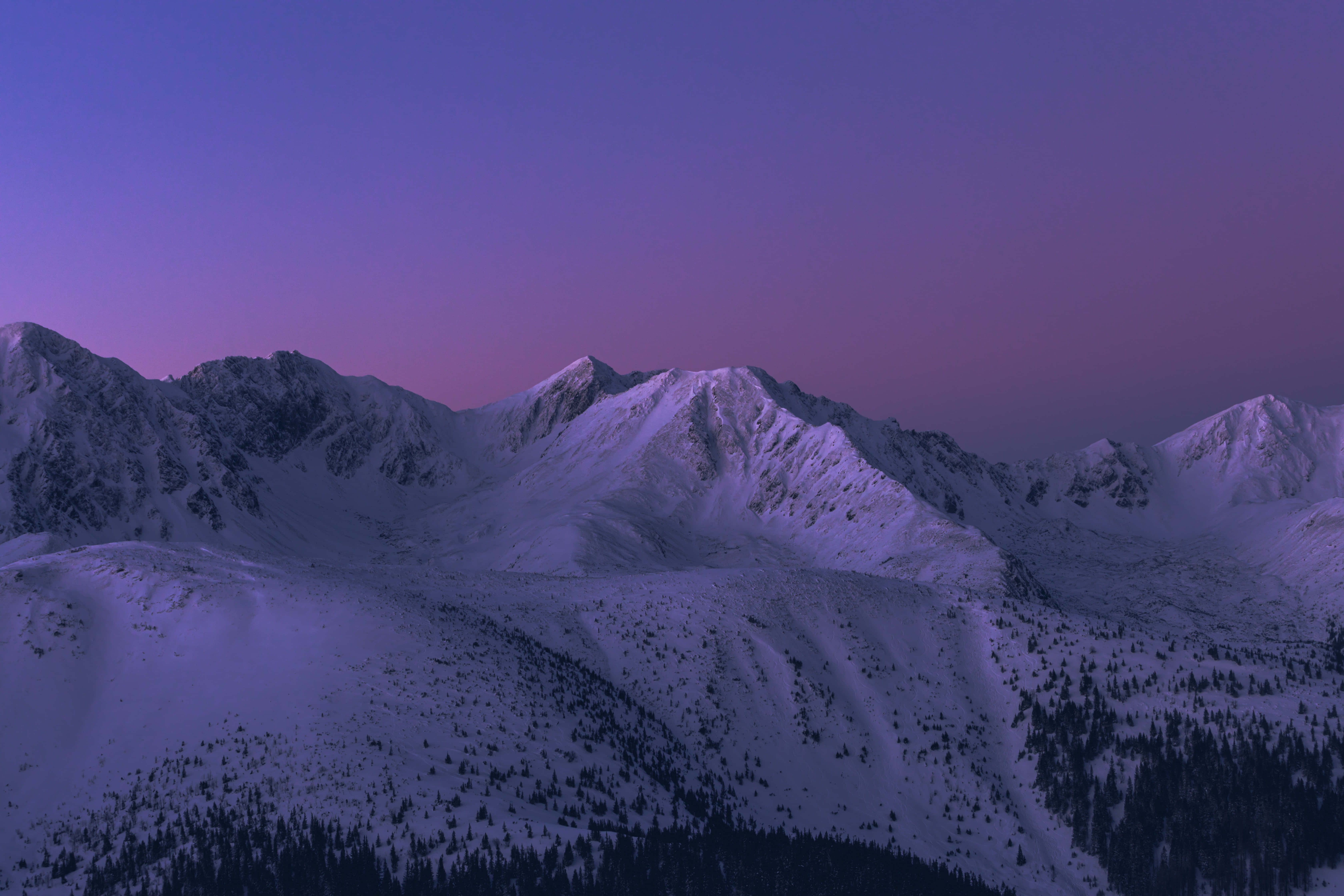 以免費背景啟發創意 壁紙 — 積雪的山峰在充滿活力的紫色和粉紅色暮色天空下閃耀。