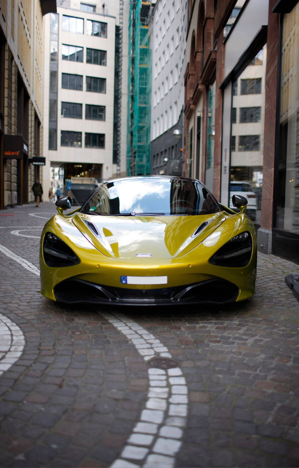 黃色McLaren跑車停泊在鵝卵石城市街道上。