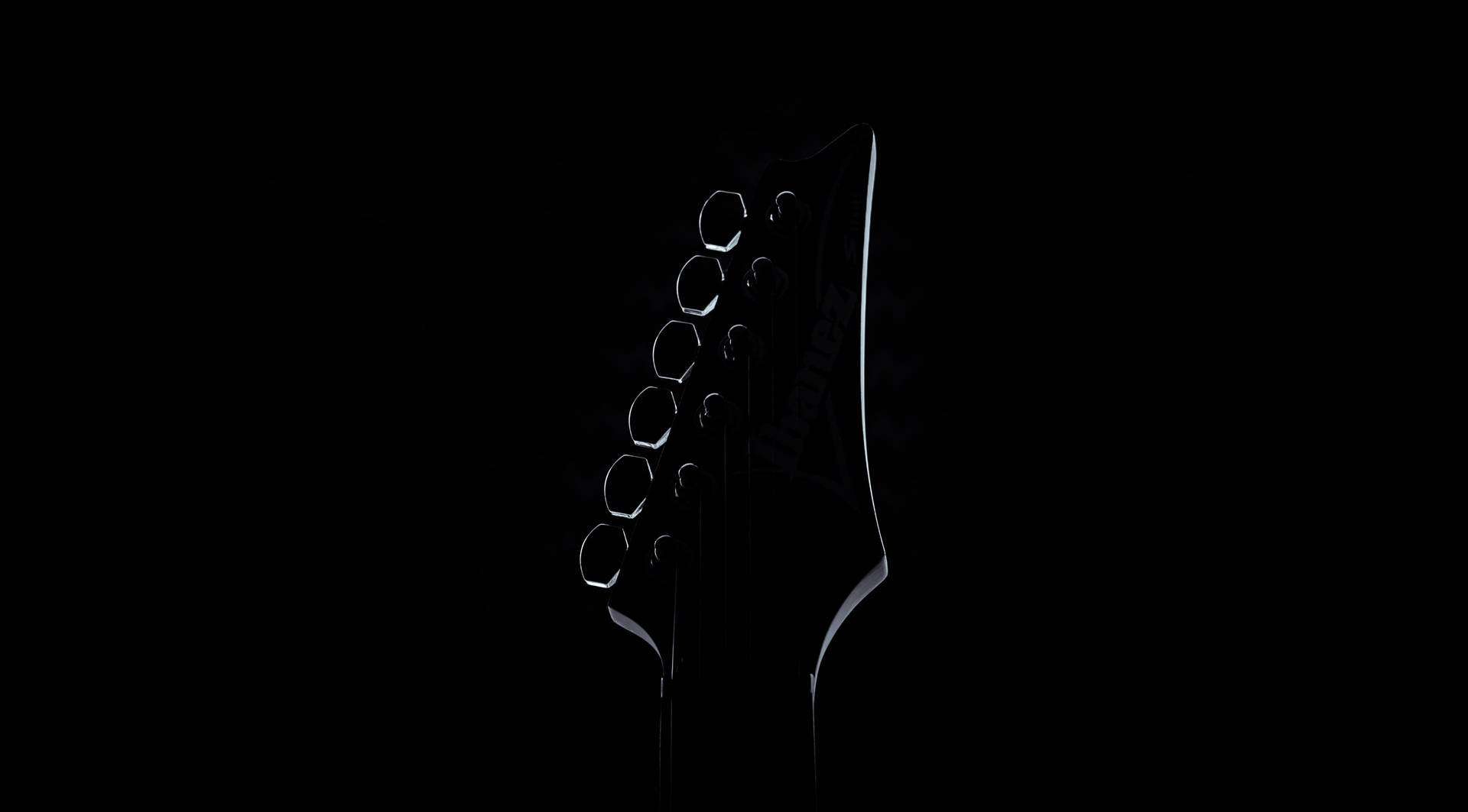 Ibanez 結他頭部在黑色背景上以柔和光線呈現輪廓。