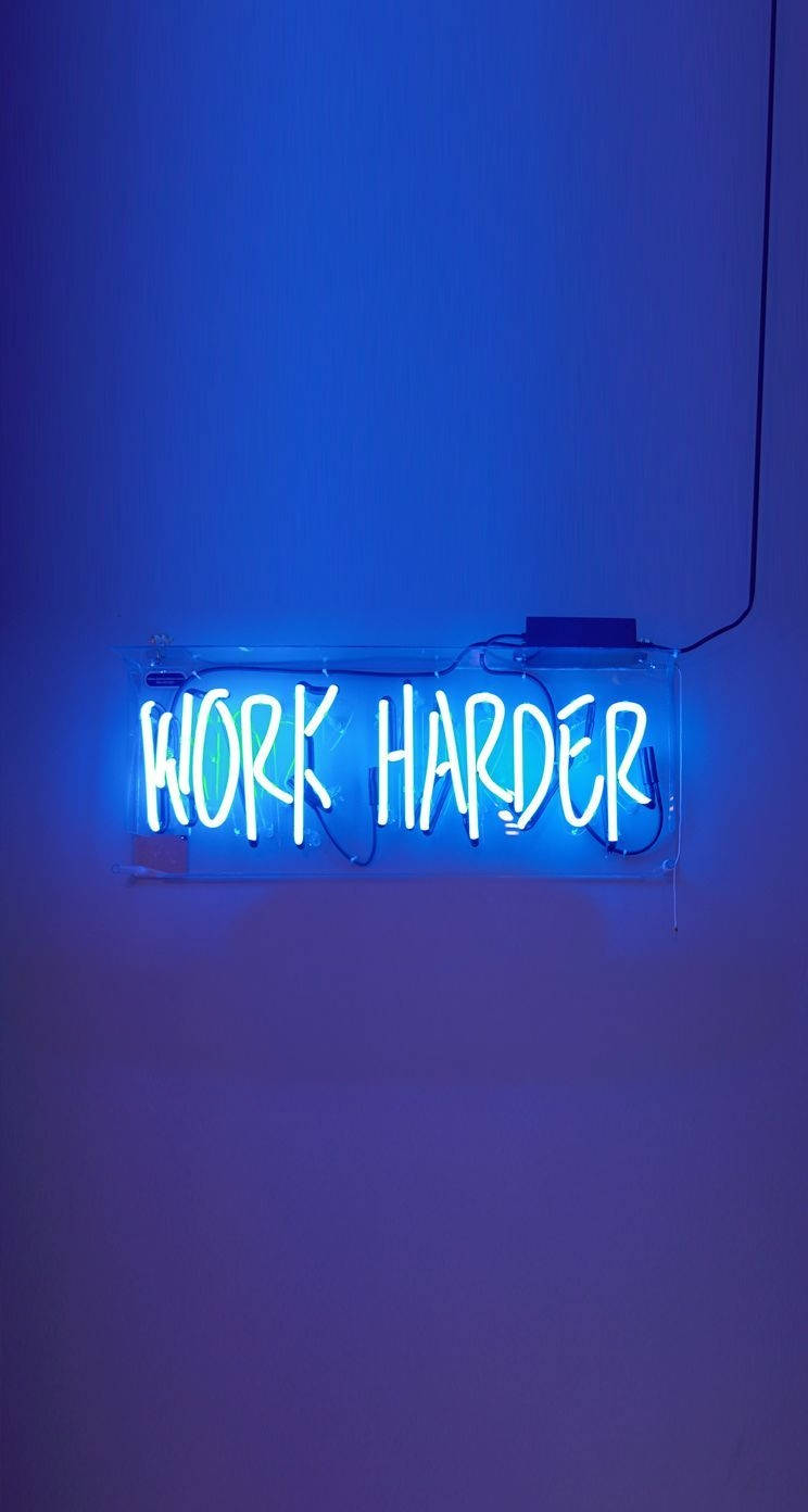 素牆上帶有 work harder 字樣的藍色霓虹燈牌。