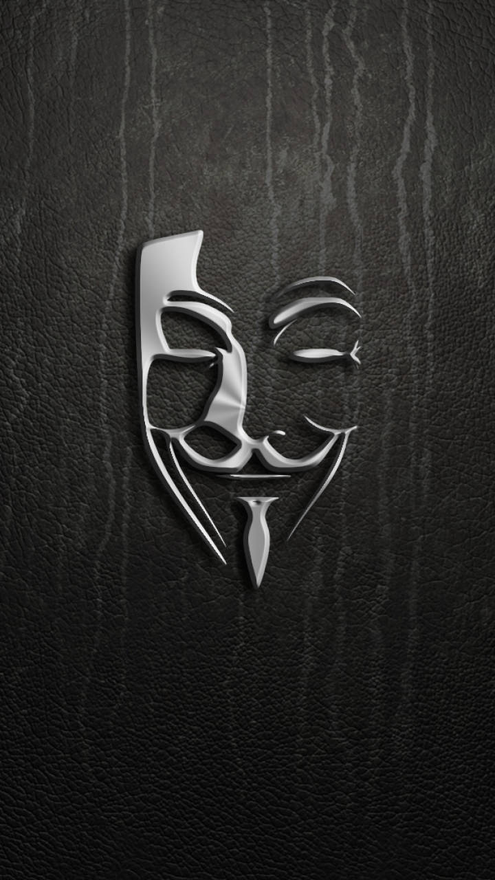 以匿名保護隱私，揭發不公 壁紙 — 金屬銀色蓋伊·福克斯面具壓印在帶有垂直皺紋的紋理黑色皮革上。