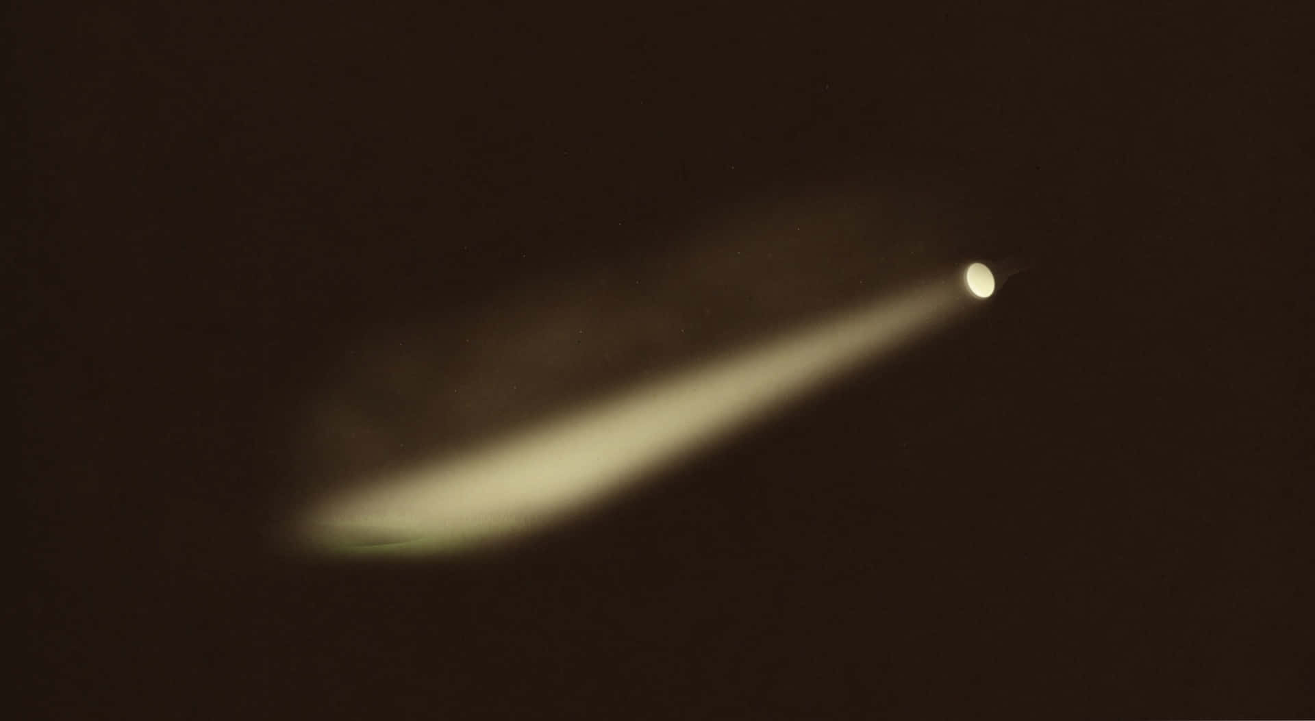 以可靠手電筒照亮黑暗 壁紙 — 一顆彗星在深棕色宇宙背景下發出柔和黃色尾巴的光芒。