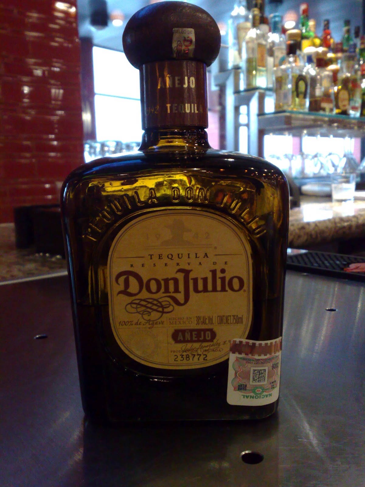 一瓶Don Julio Añejo龍舌蘭酒在酒吧，後面有紅磚牆和架子。
