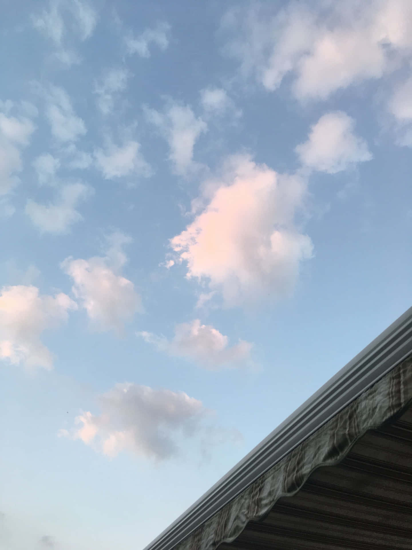 粉紅色和白色雲朵在黃昏時分飄浮在圖案遮陽篷上方。