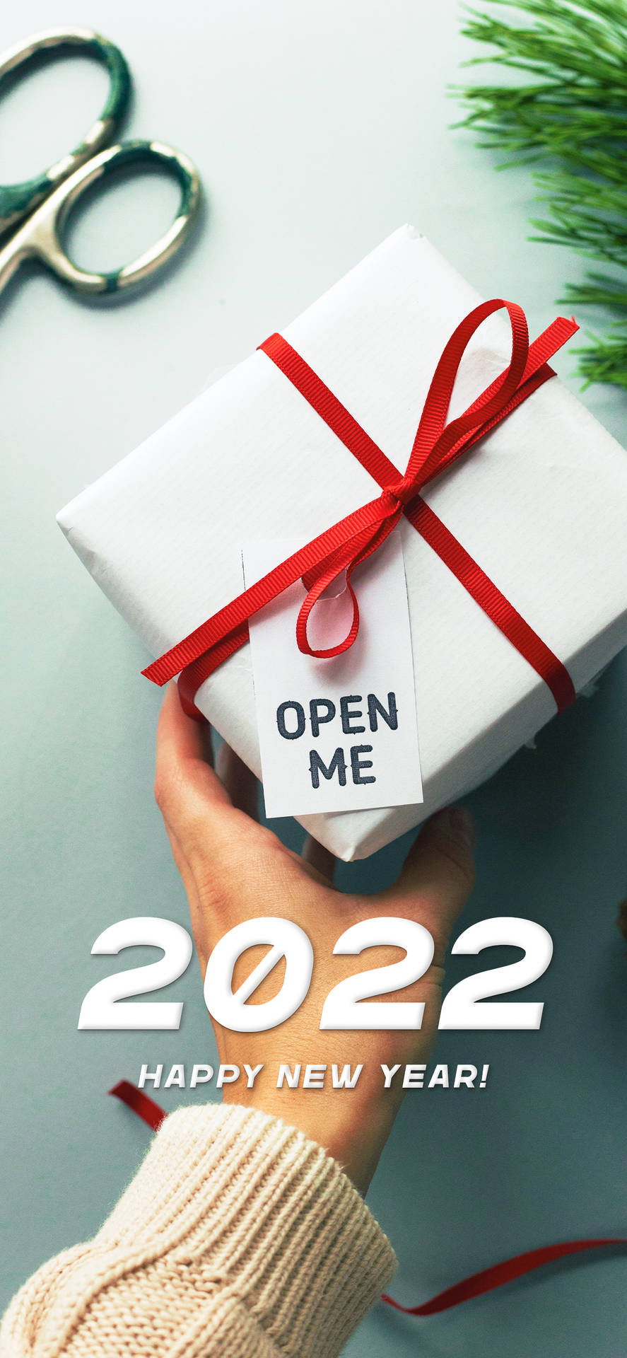 手拿著白色禮物盒，帶有紅色絲帶和「打開我」標籤，用於2022年新年。
