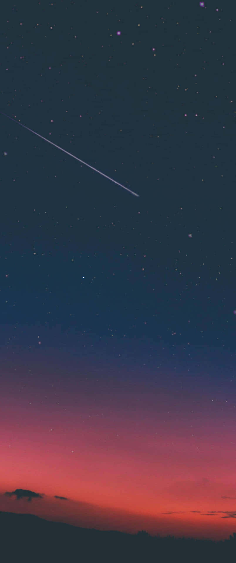 流星劃過暮色天空，下方是黑暗的山丘