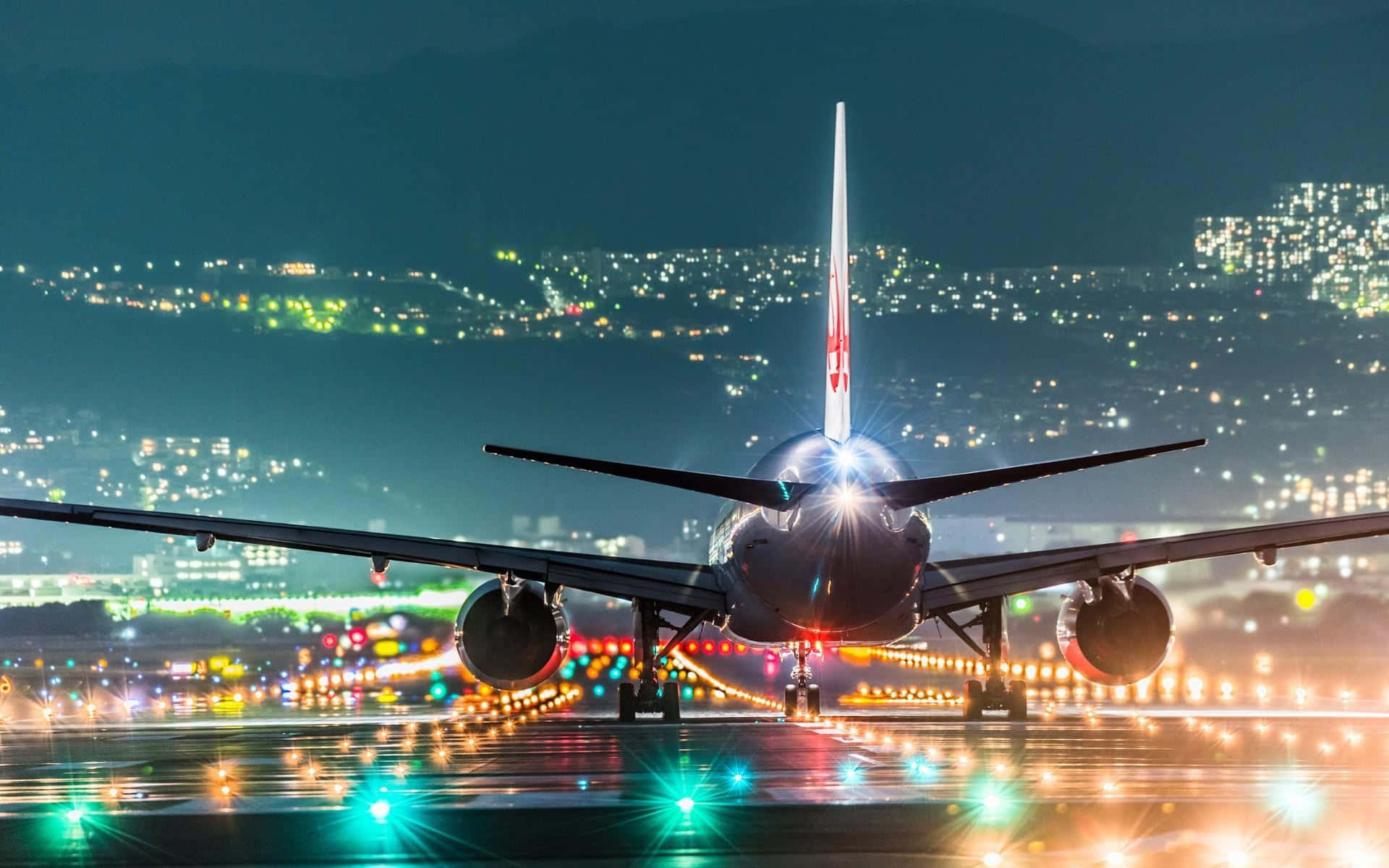 一架大型飛機在夜間停在濕滑的跑道上，背景有城市燈光。