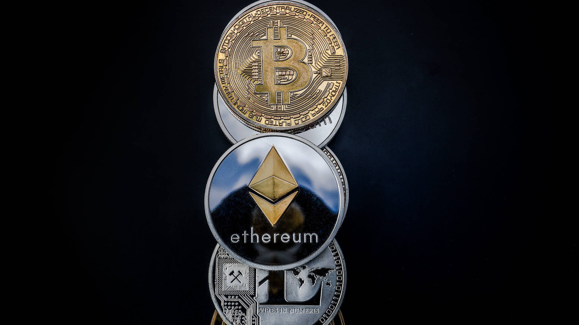 以太幣硬幣排成一線 壁紙 — 堆疊的實體加密貨幣硬幣，包括比特幣和以太幣，在深色背景上。