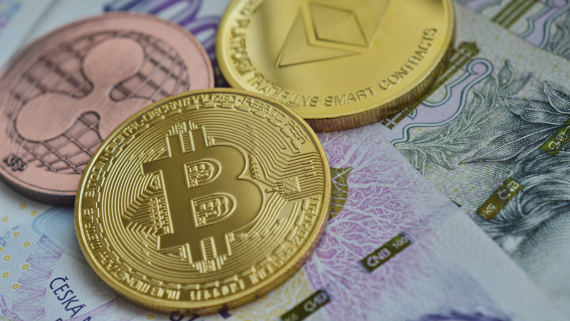 以太幣硬幣疊在鈔票上 壁紙 — 金色比特幣、以太幣和萊特幣硬幣放在捷克克朗紙幣上，構成特寫金融構圖。