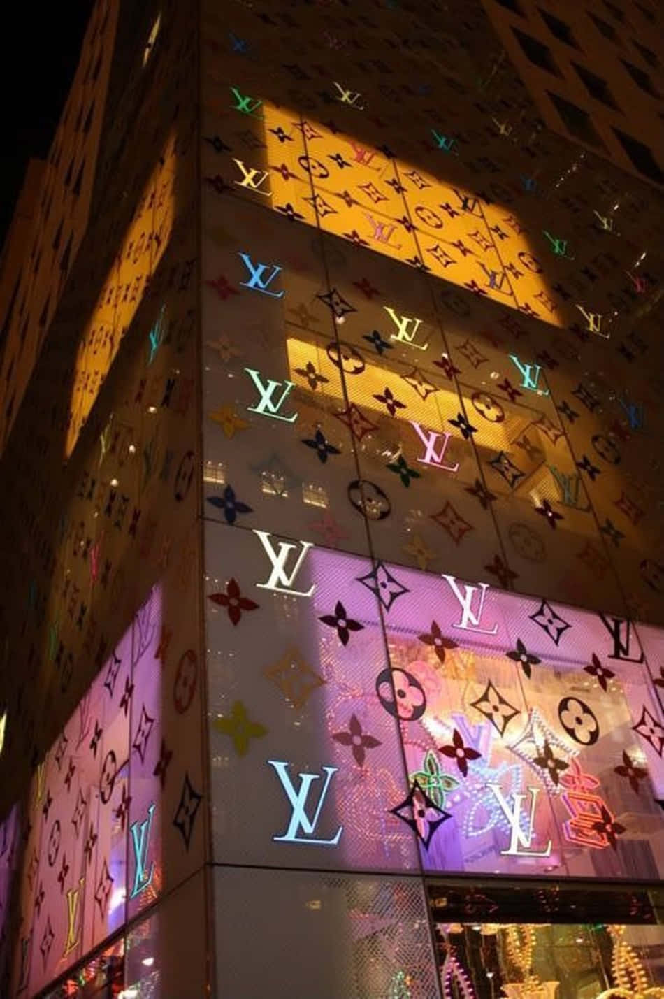 夜晚的豪華建築，玻璃外牆上有發光的多色字母圖案。