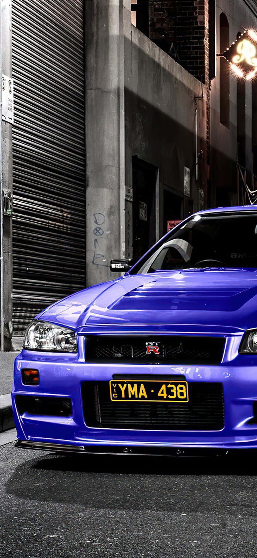 藍色日產Skyline R34停泊在黑暗小巷中，帶有塗鴉和霓虹燈光。