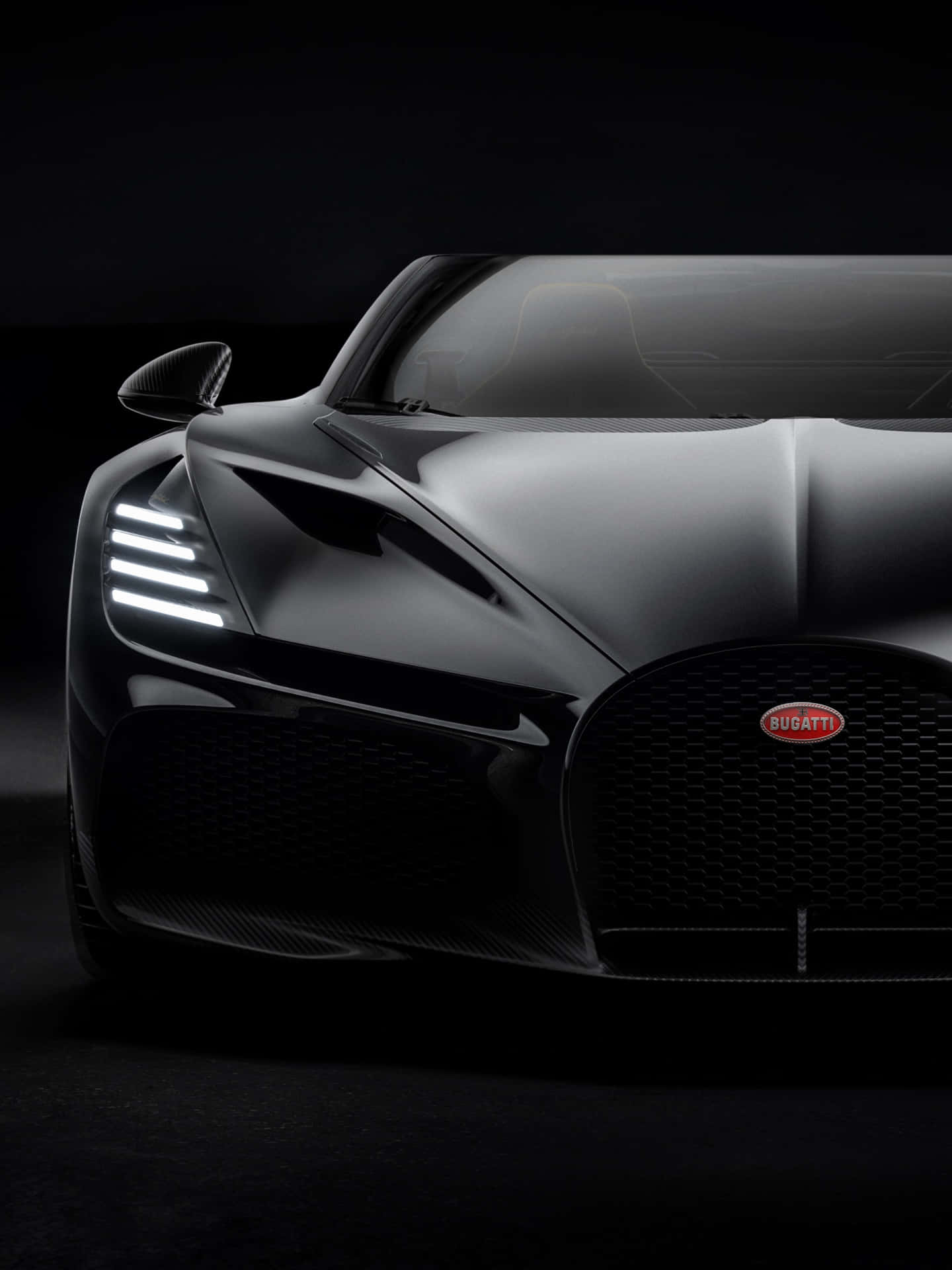 黑色Bugatti超級跑車在黑暗的攝影棚中車頭燈發光的特寫。