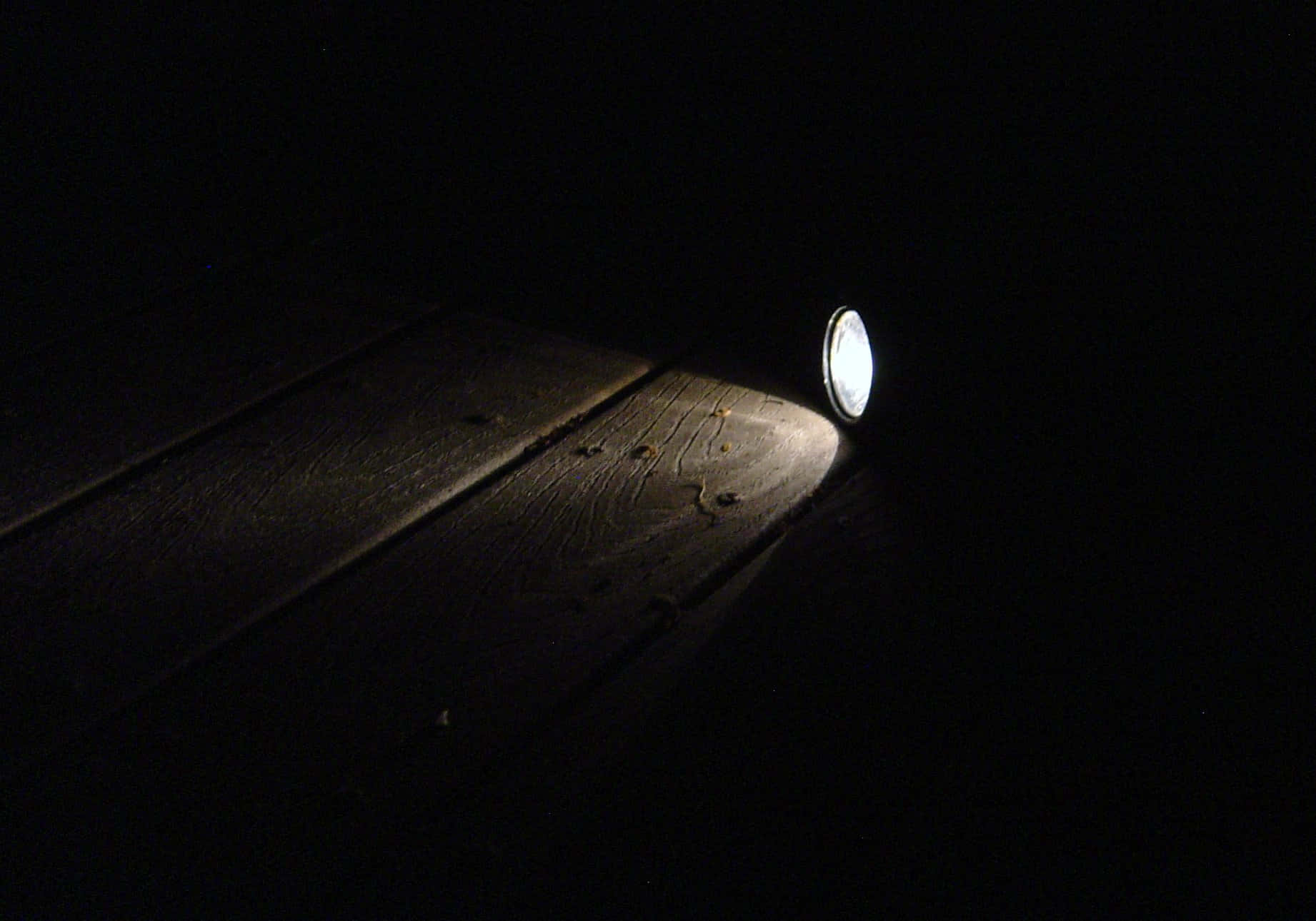 以強勁 LED 手電筒照亮前路 壁紙 — 一道手電筒光束劃破黑暗，照亮夜間甲板上風化的木板。