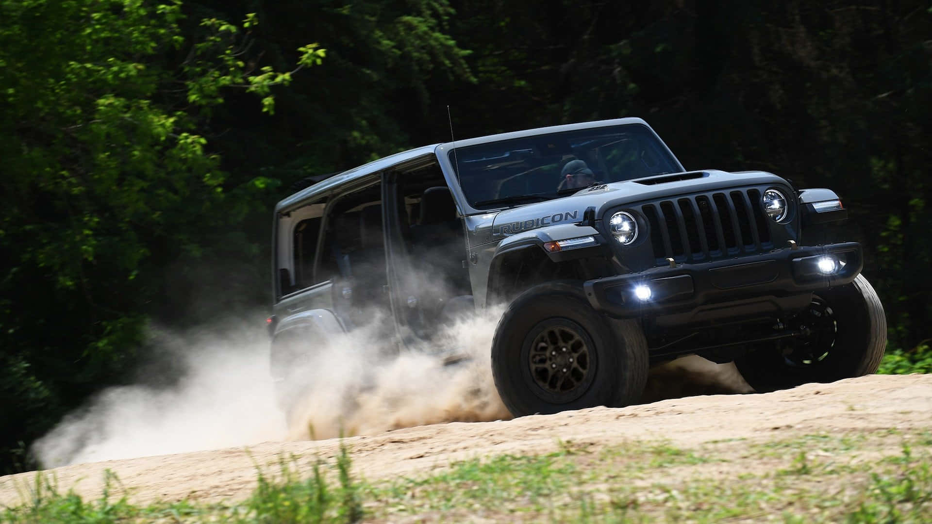 灰色Jeep Wrangler Rubicon在森林的泥土小徑上行駛