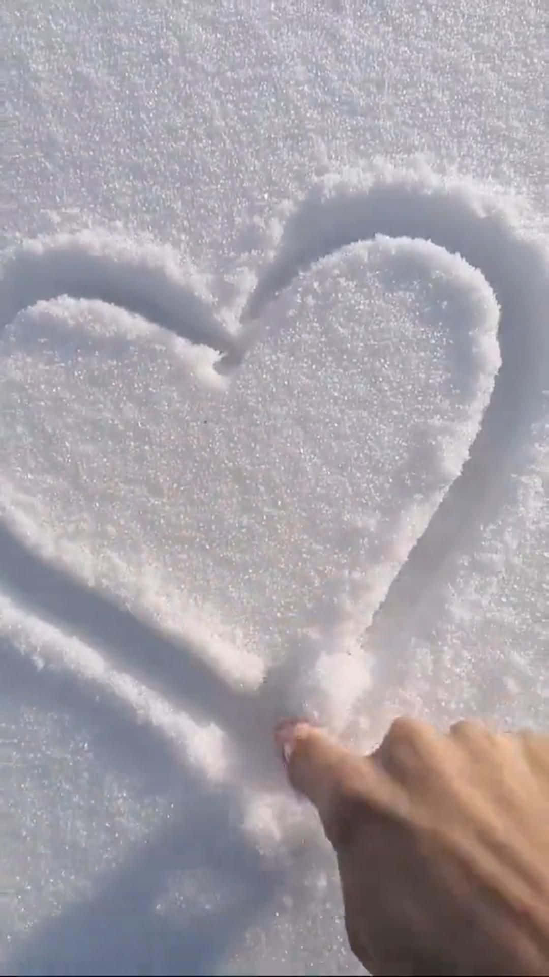 以愛美化世界 壁紙 — 一隻手在潔白的新雪上畫出心形，明亮的陽光投下柔和的陰影。