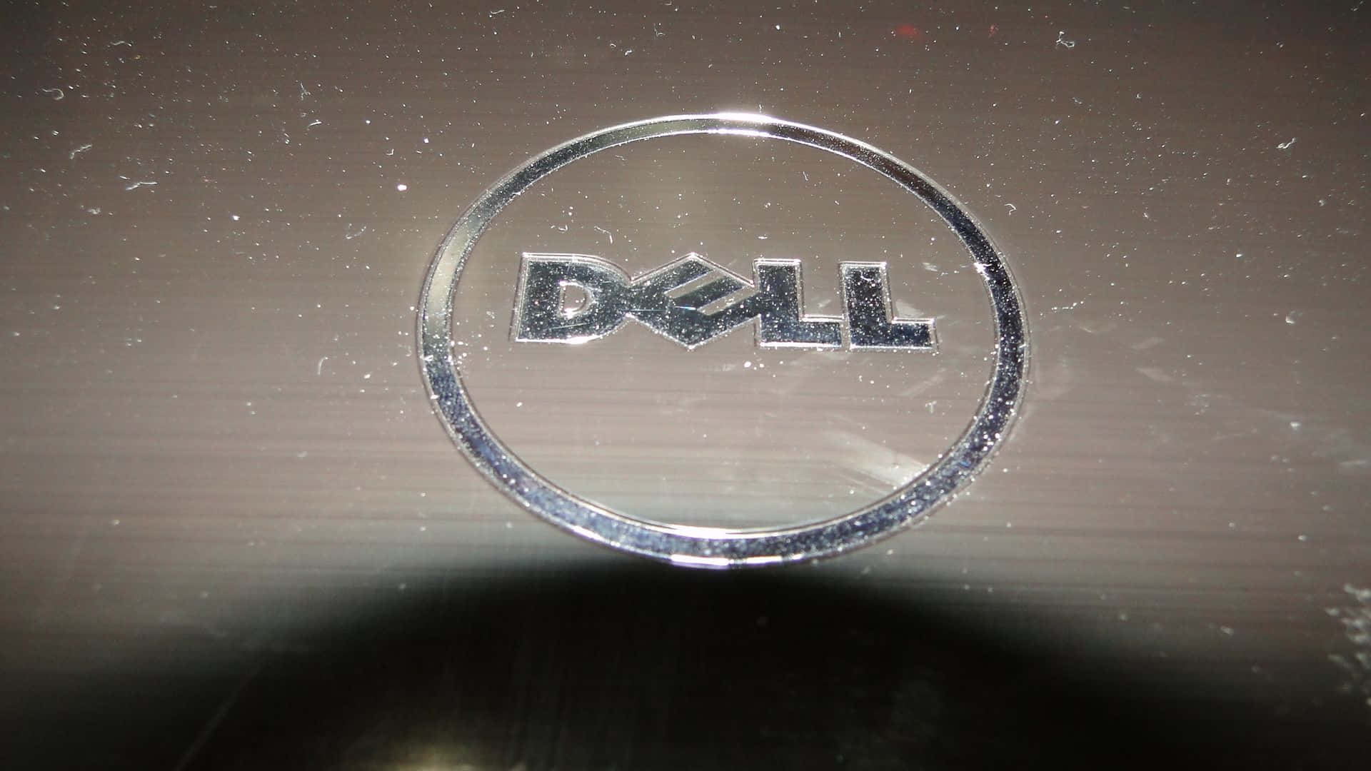 金屬表面上有灰塵和刮痕的 Dell 筆記型電腦標誌。