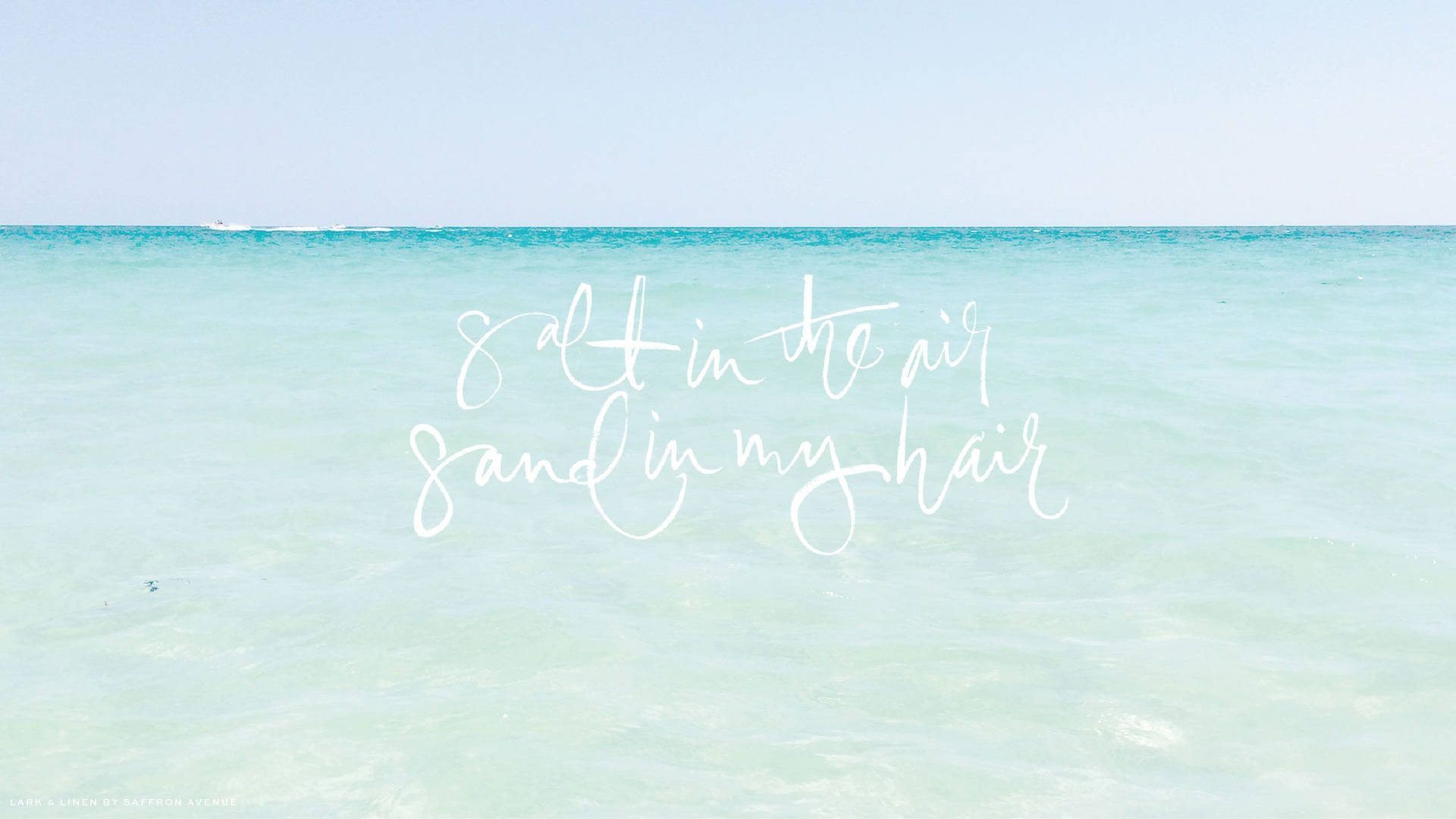 平靜的藍綠色海洋上白色文字寫著 salt in the air sand in my hair。