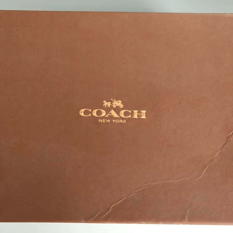 棕色 Coach New York 品牌盒子，帶有金色標誌和可見摺痕。