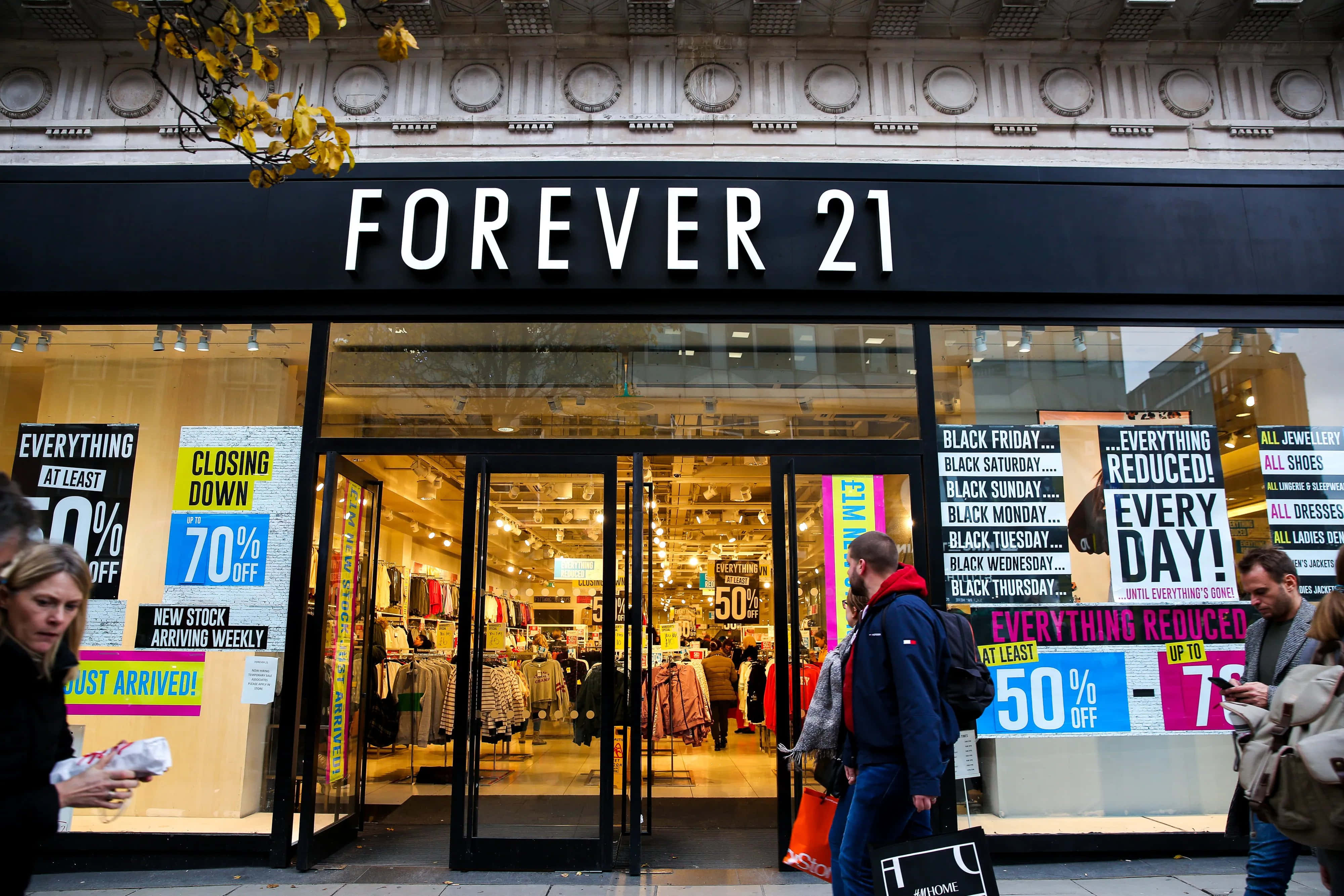以時尚又實惠的產品打造你的衣櫥，來自Forever 21 壁紙 — 一間熙熙攘攘的Forever 21商店，帶有醒目的減價標誌和購物者走過其玻璃門。