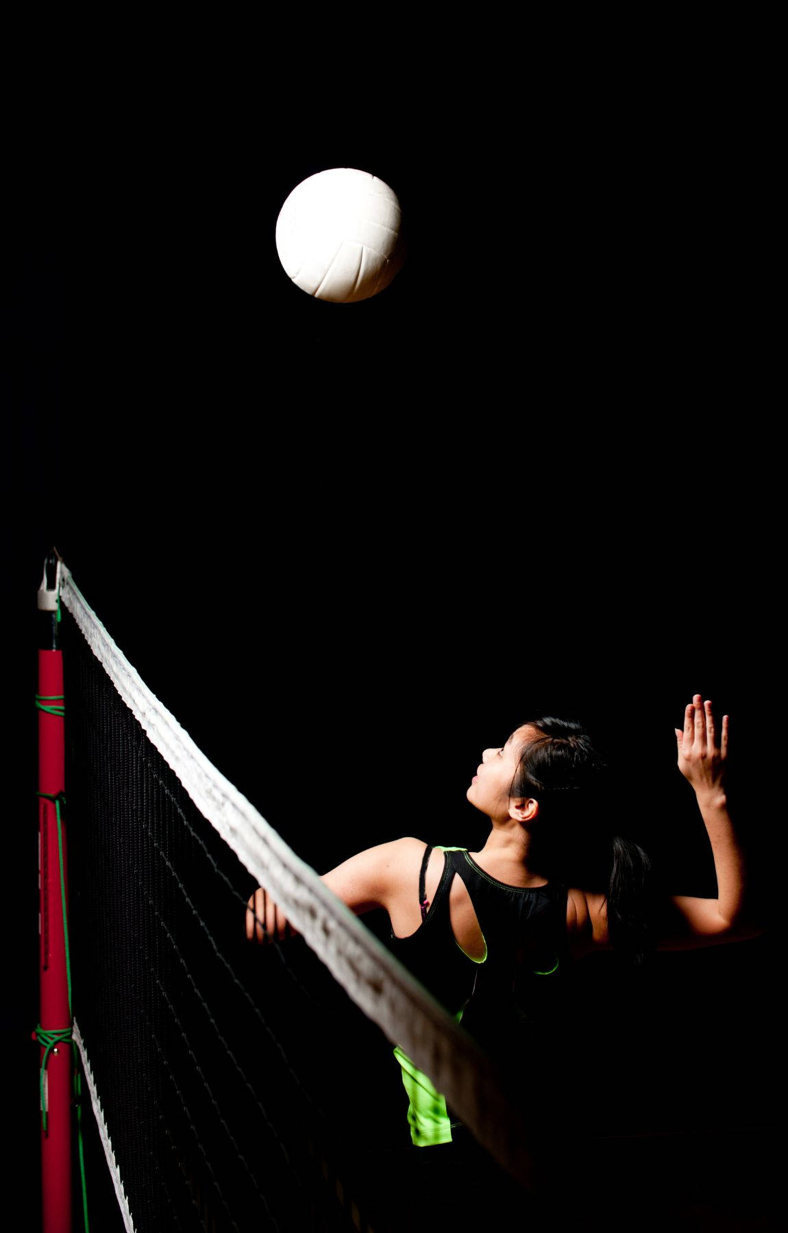 女子排球運動員在戲劇性燈光下扣球。