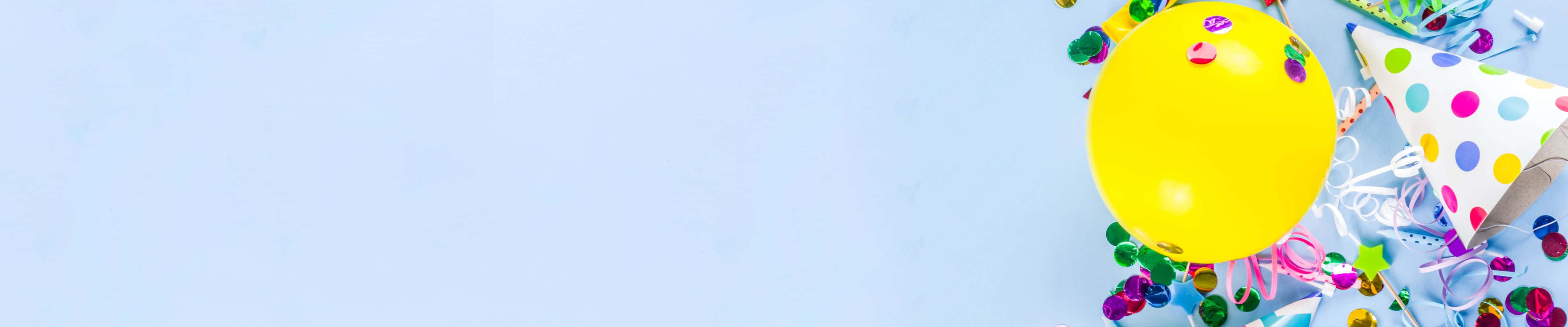 以時尚姿態脫穎而出 壁紙 — 一個鮮黃色氣球和彩色派對帽放在淺藍色表面上，周圍環繞著節日五彩紙屑。