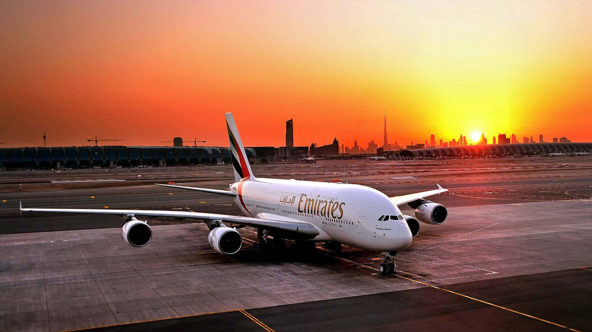 日落時分，阿聯酋航空A380飛機停在停機坪上，背景是杜拜天際線。