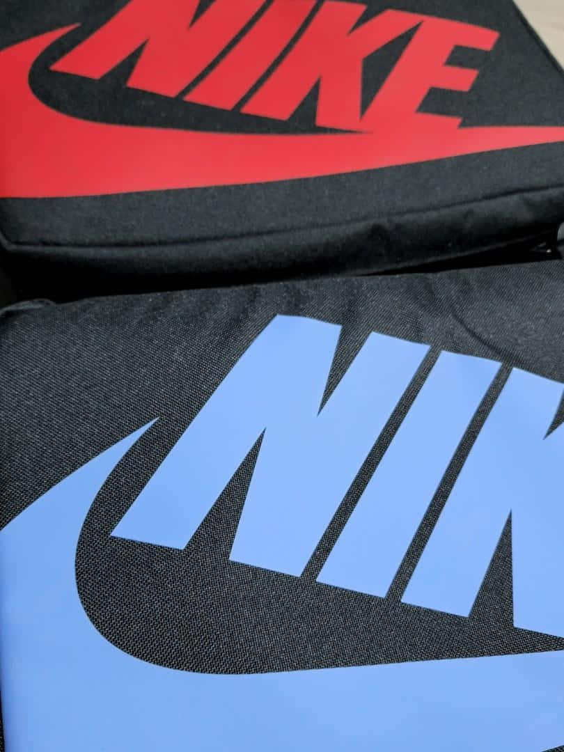 兩個Nike品牌袋，帶有紅色和藍色標誌，位於黑色布料上。
