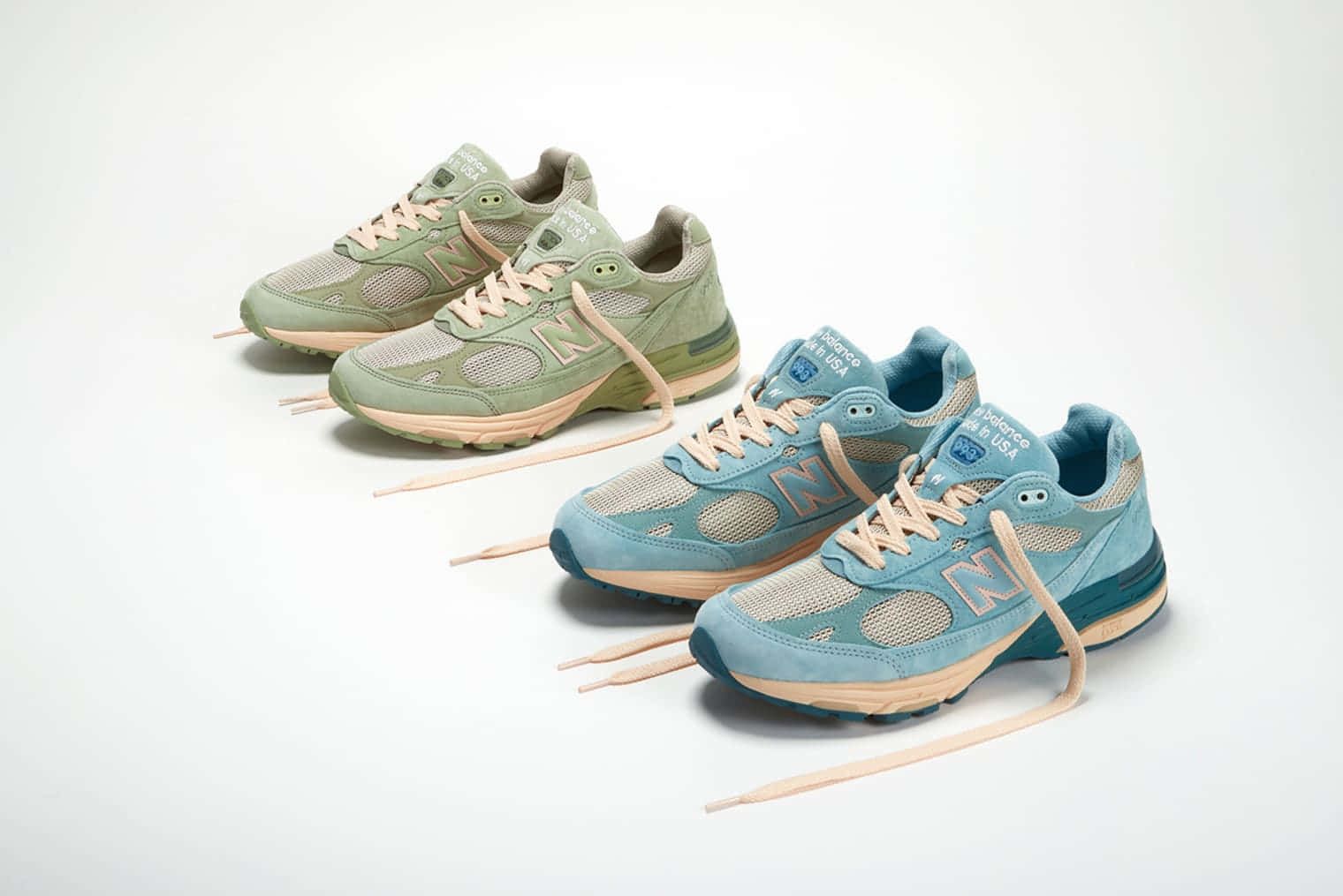 兩對 New Balance 運動鞋，綠色和藍色調，米色鞋帶，白色背景。