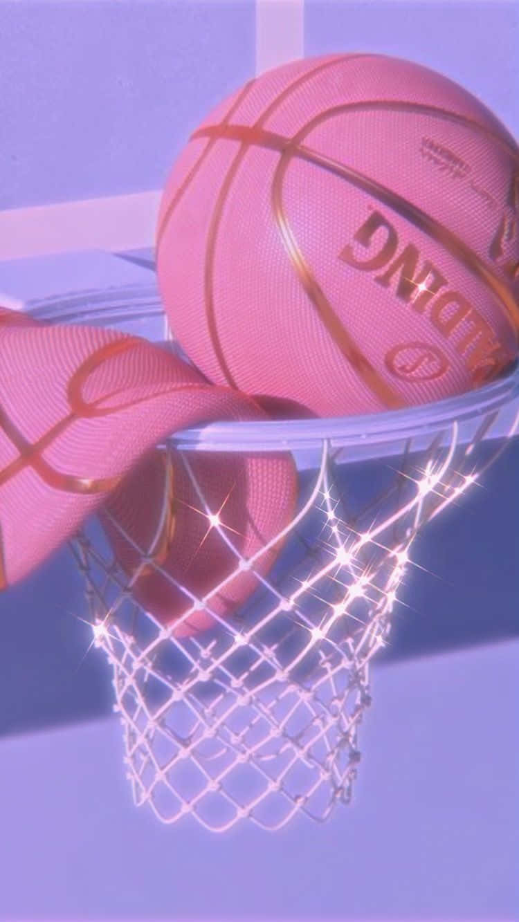 以時尚運動風格，一切皆有可能 - Pink Sports 壁紙 — 一個帶有金色線條的粉紅色籃球懸掛在發光的網中，背景是柔和的紫色，帶有閃爍的光芒。