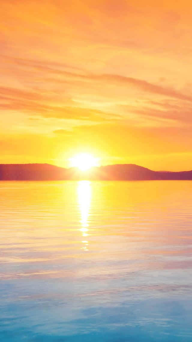 夕陽下的平靜湖面，遠方有山丘