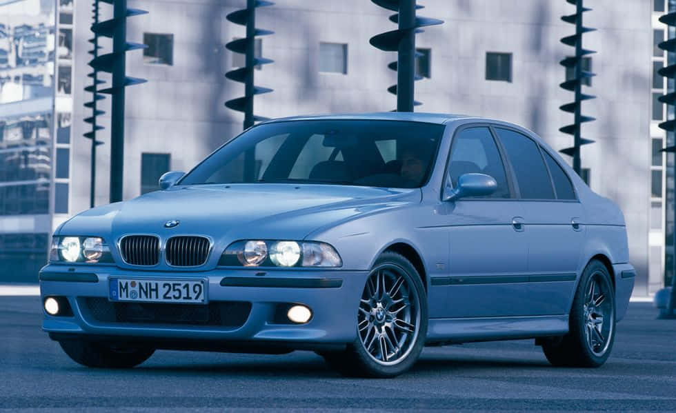 藍色BMW房車停泊在城市街道上，背景有現代建築。