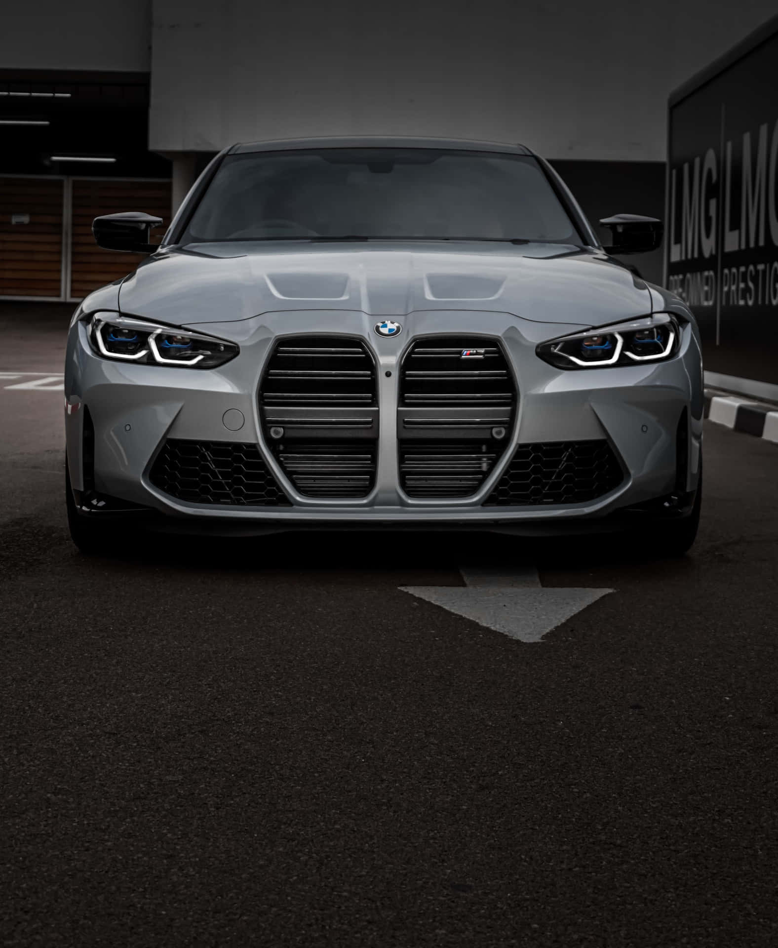 銀色BMW M3跑車停泊在黑暗的車庫中，車頭燈閃爍。