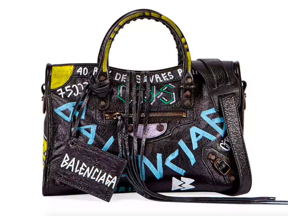 黑色皮革 Balenciaga 手袋，帶有彩色塗鴉文字和流蘇。
