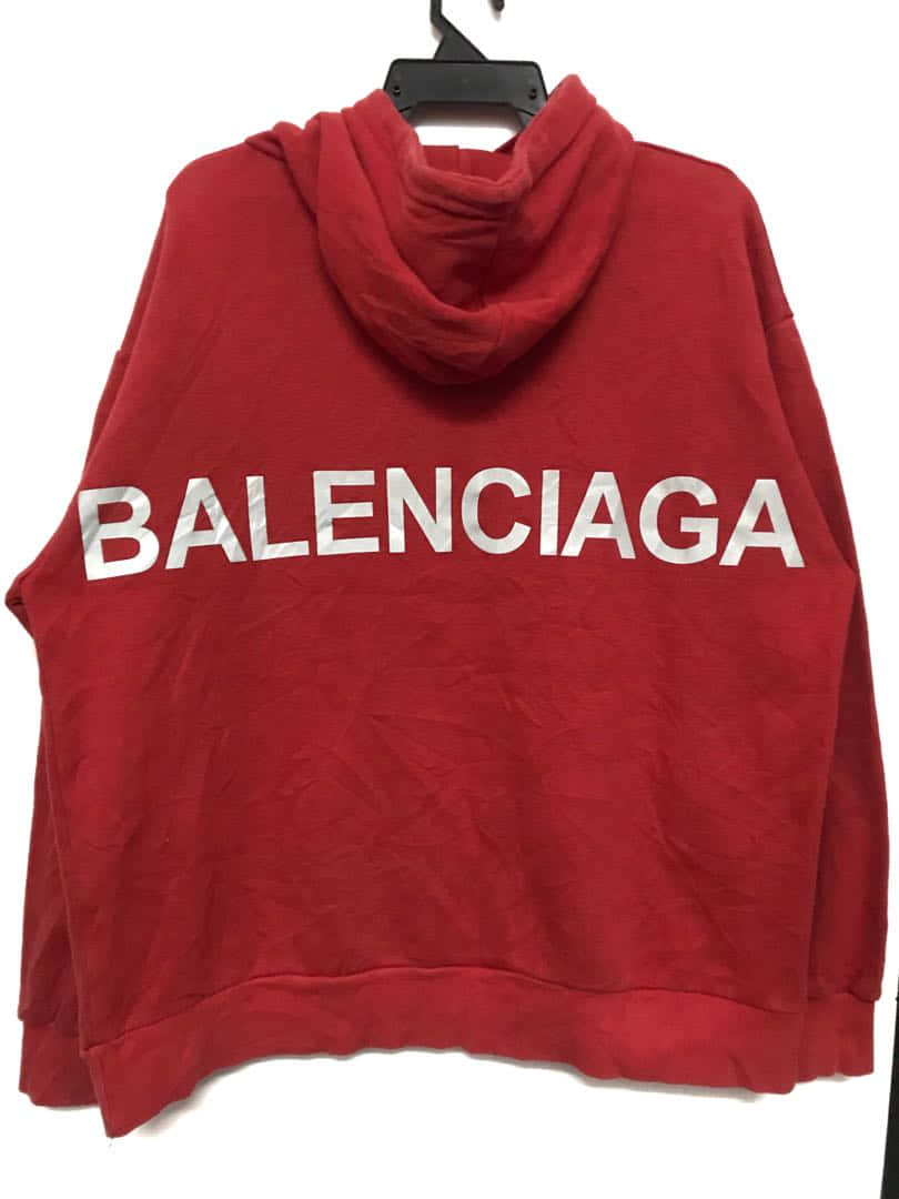 紅色 Balenciaga 連帽衛衣，白色標誌，掛在黑色衣架上。