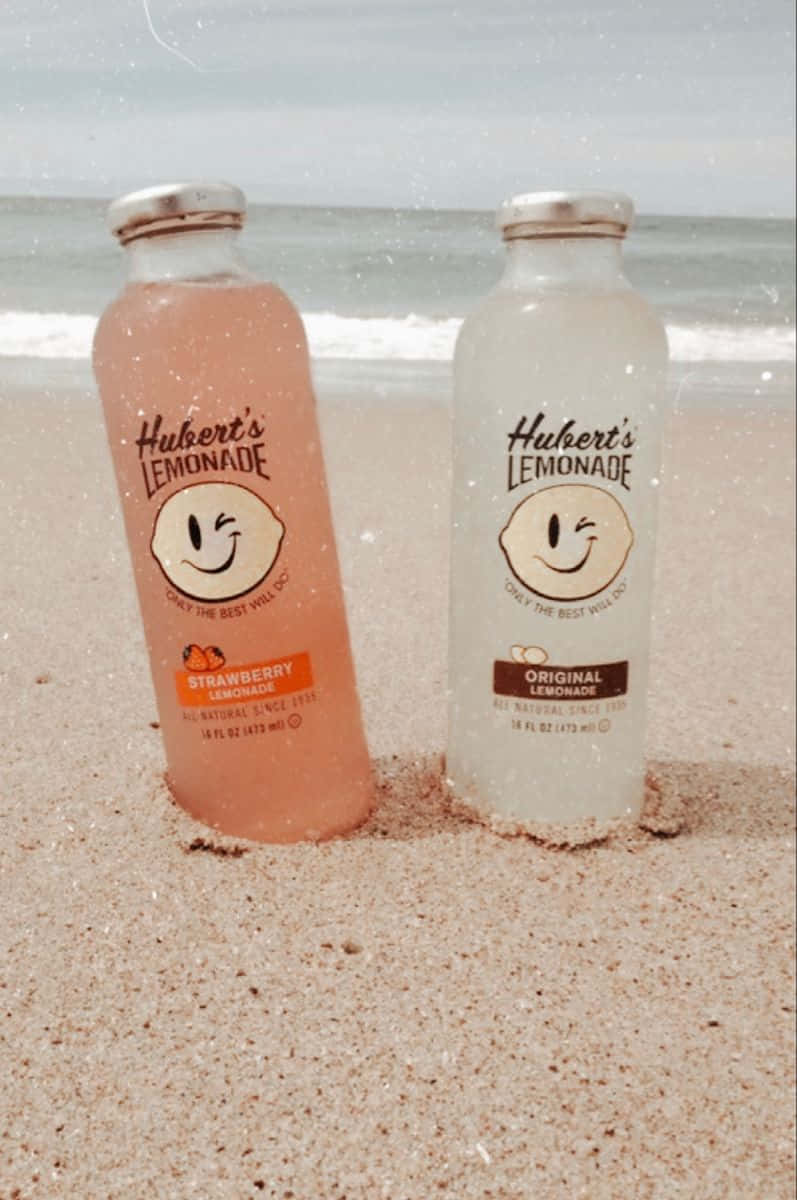沙灘上的兩瓶檸檬水，背景有海浪。