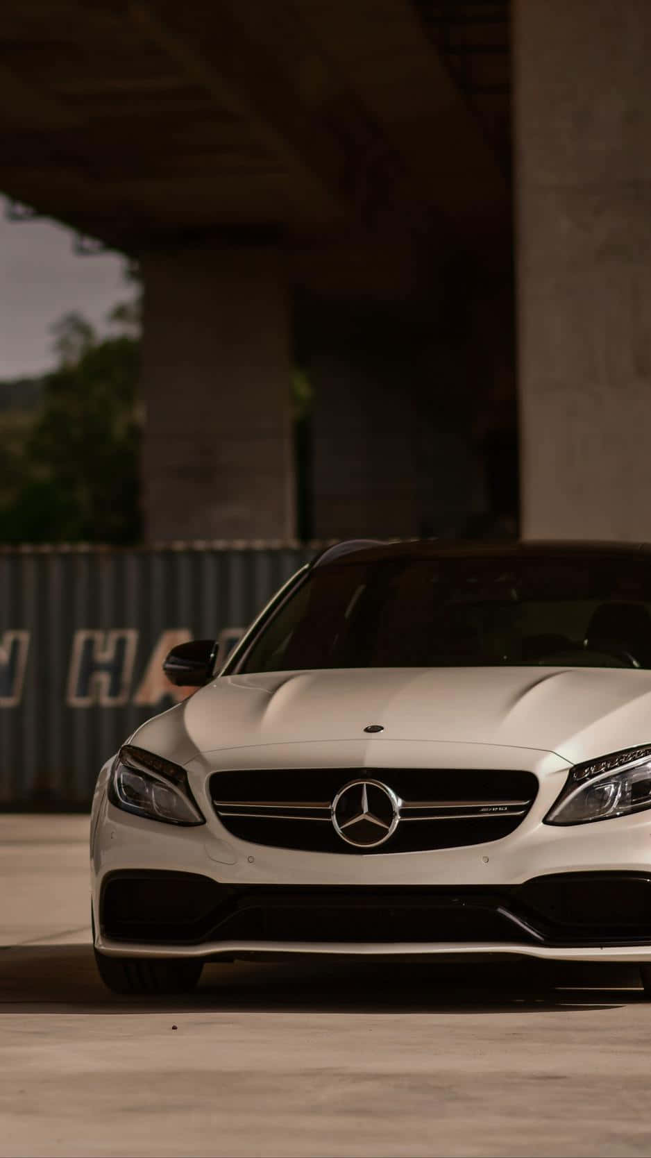 白色Mercedes-AMG停放在混凝土天橋下，帶有戲劇性的燈光效果。