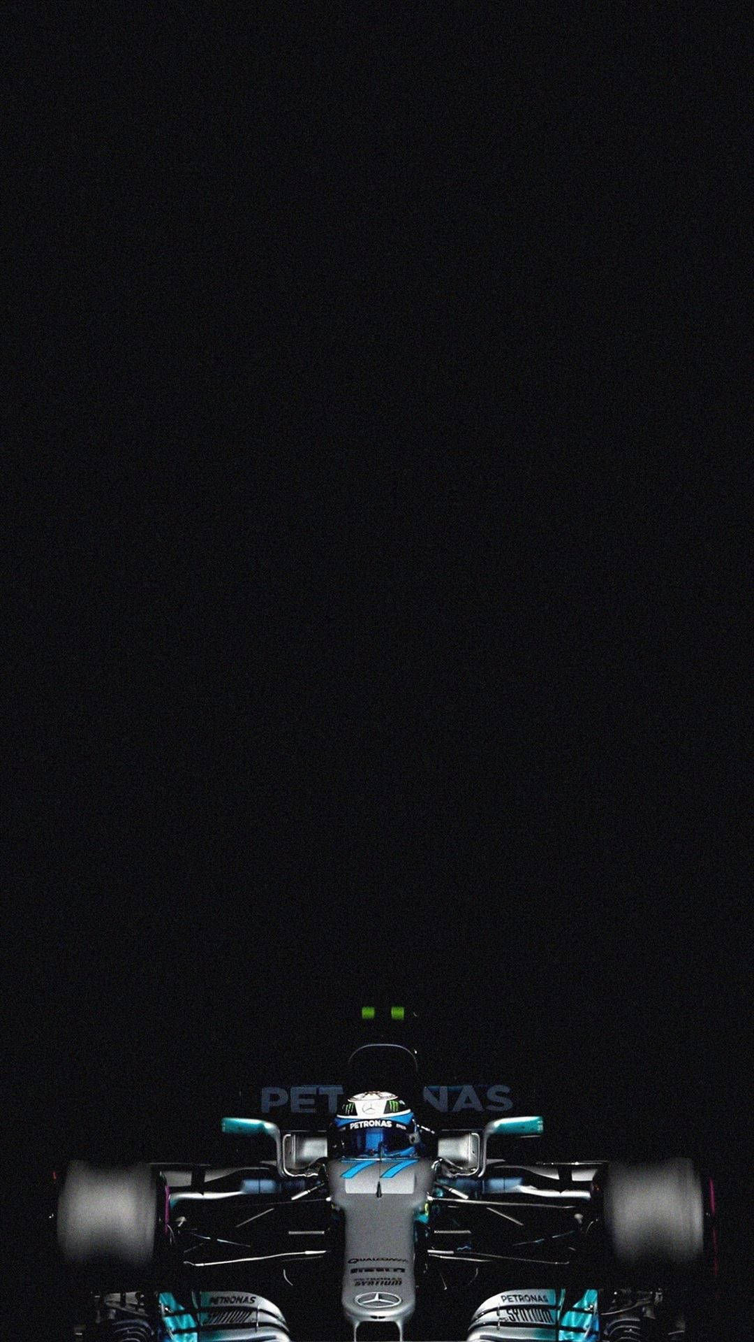 一輛一級方程式賽車在夜間被發光的綠色燈光照亮。