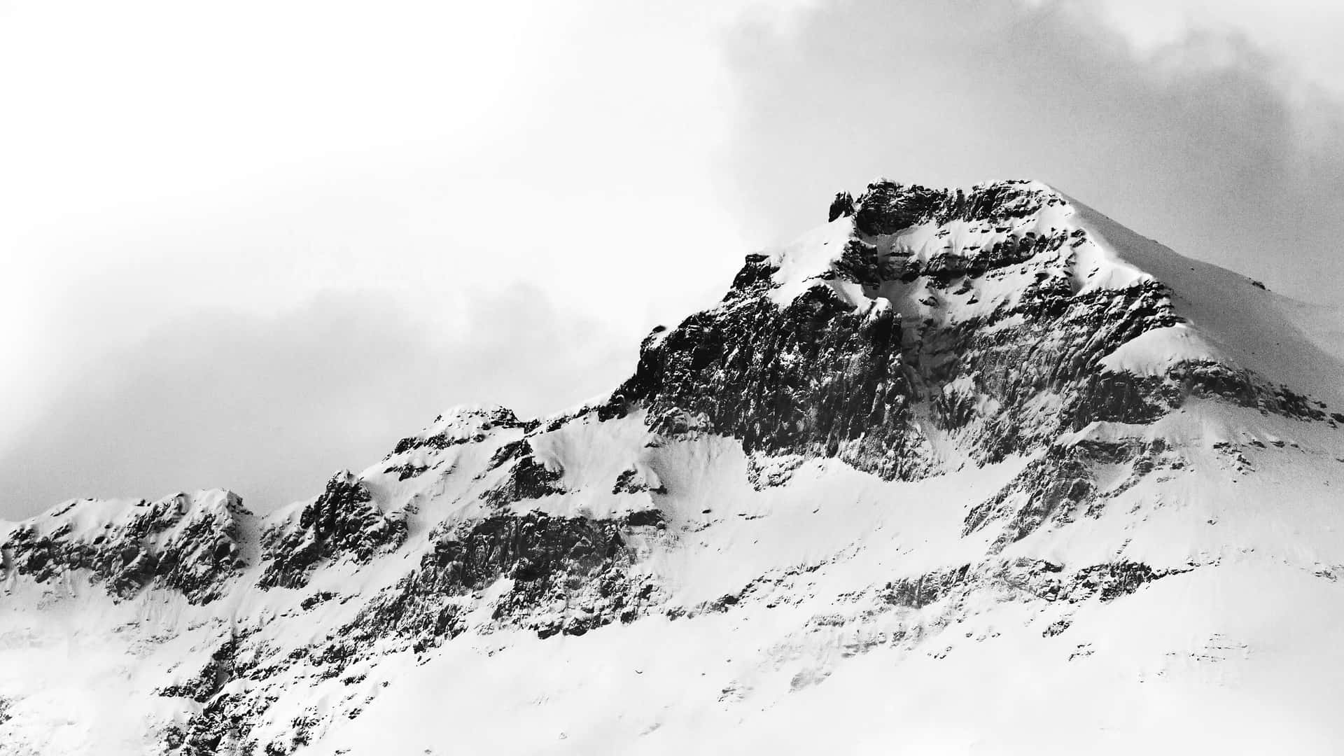 在陰天之下，一個積雪覆蓋、岩石露頭的山峰。