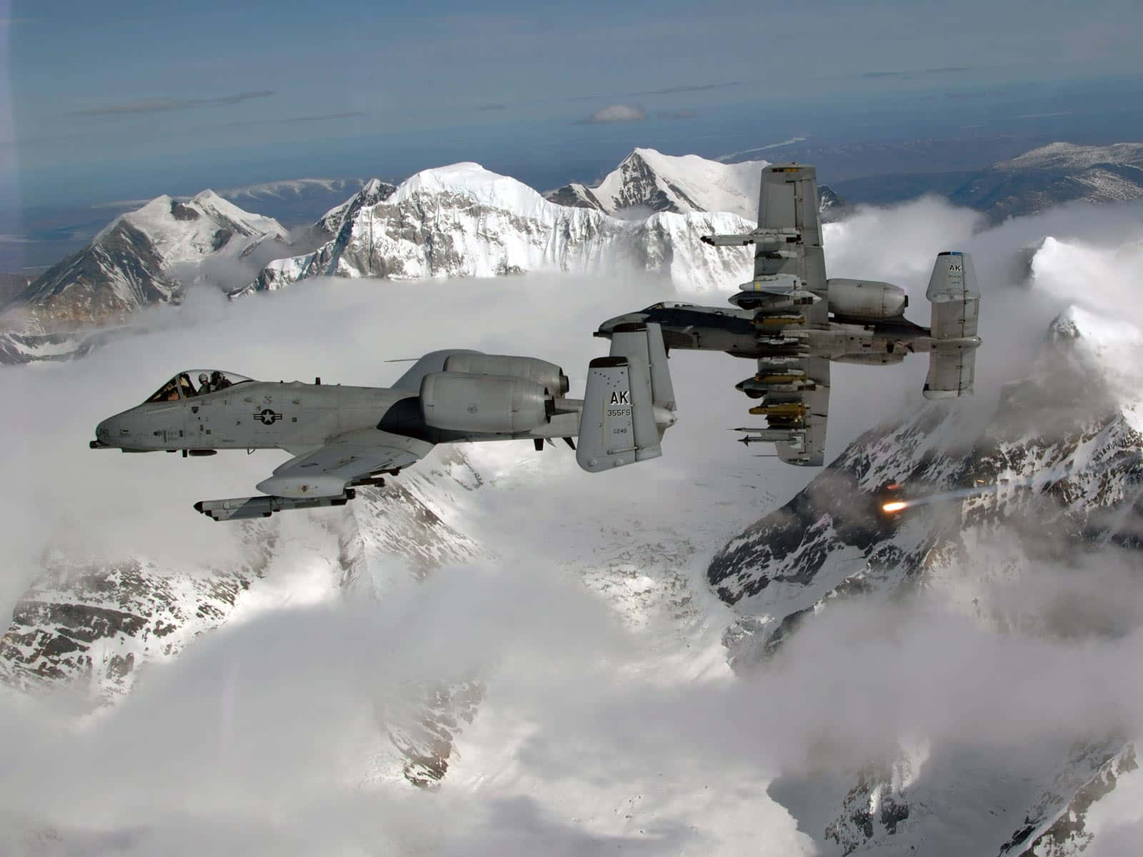 兩架軍用噴射機飛越積雪的山脈，穿過雲層發射導彈。