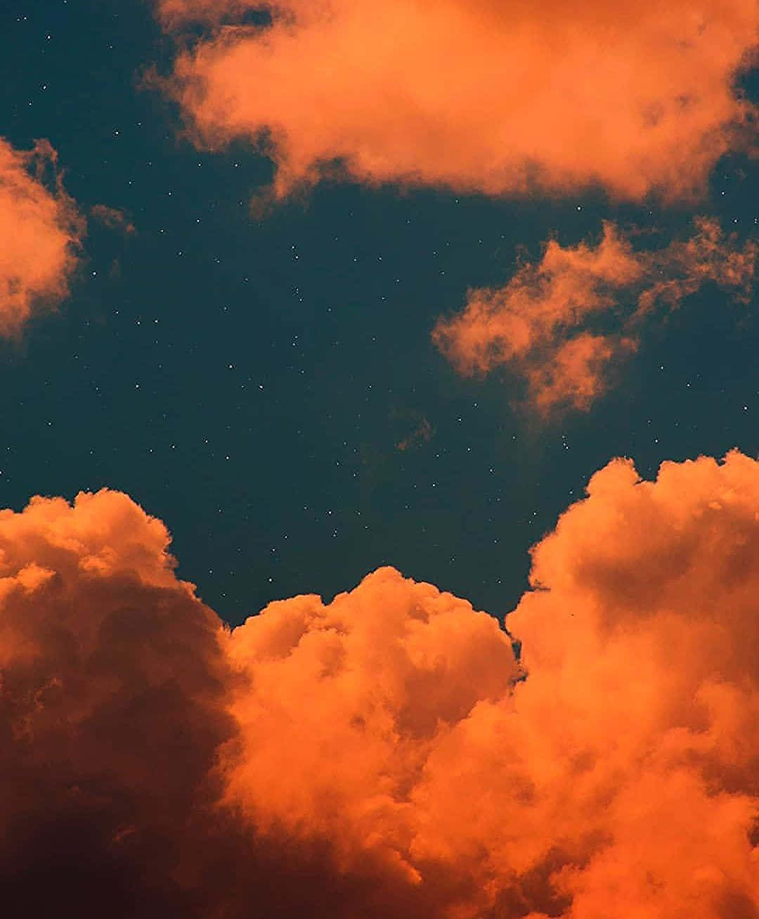 在繁星點點的夜空下被照亮的橙色雲朵。