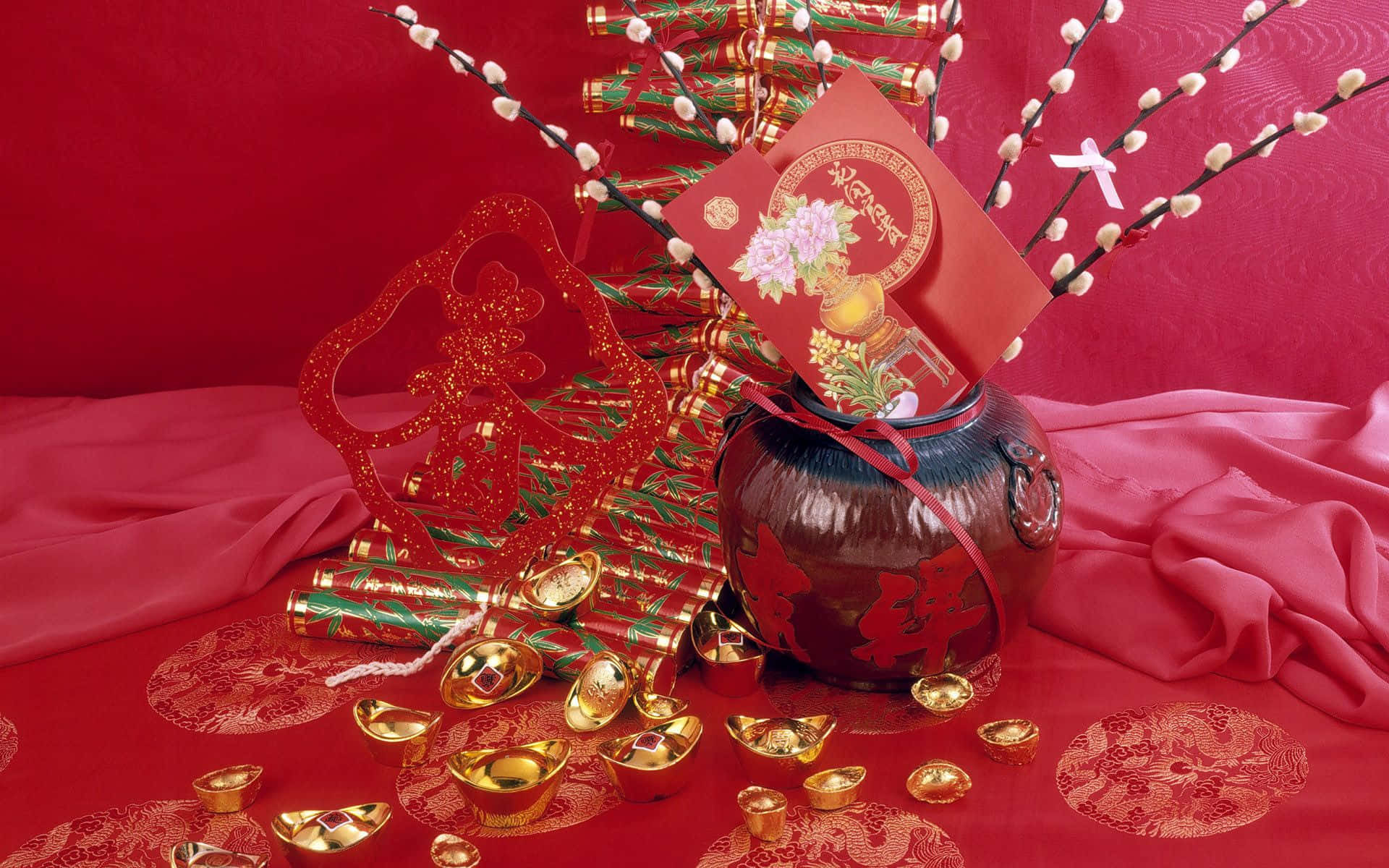 中國新年裝飾，包括紅包、金元寶和節日飾品，置於紅色布料上。