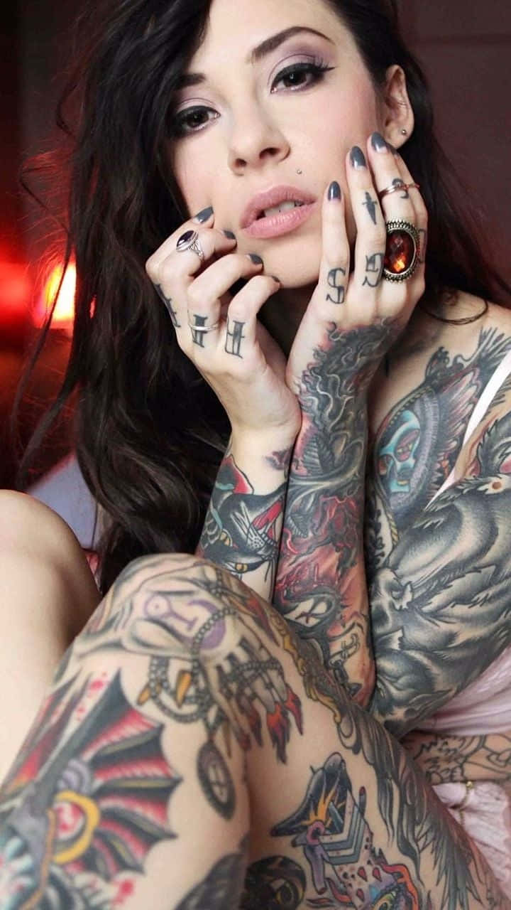 一位深色頭髮、戴著戒指的紋身女性凝視著鏡頭。