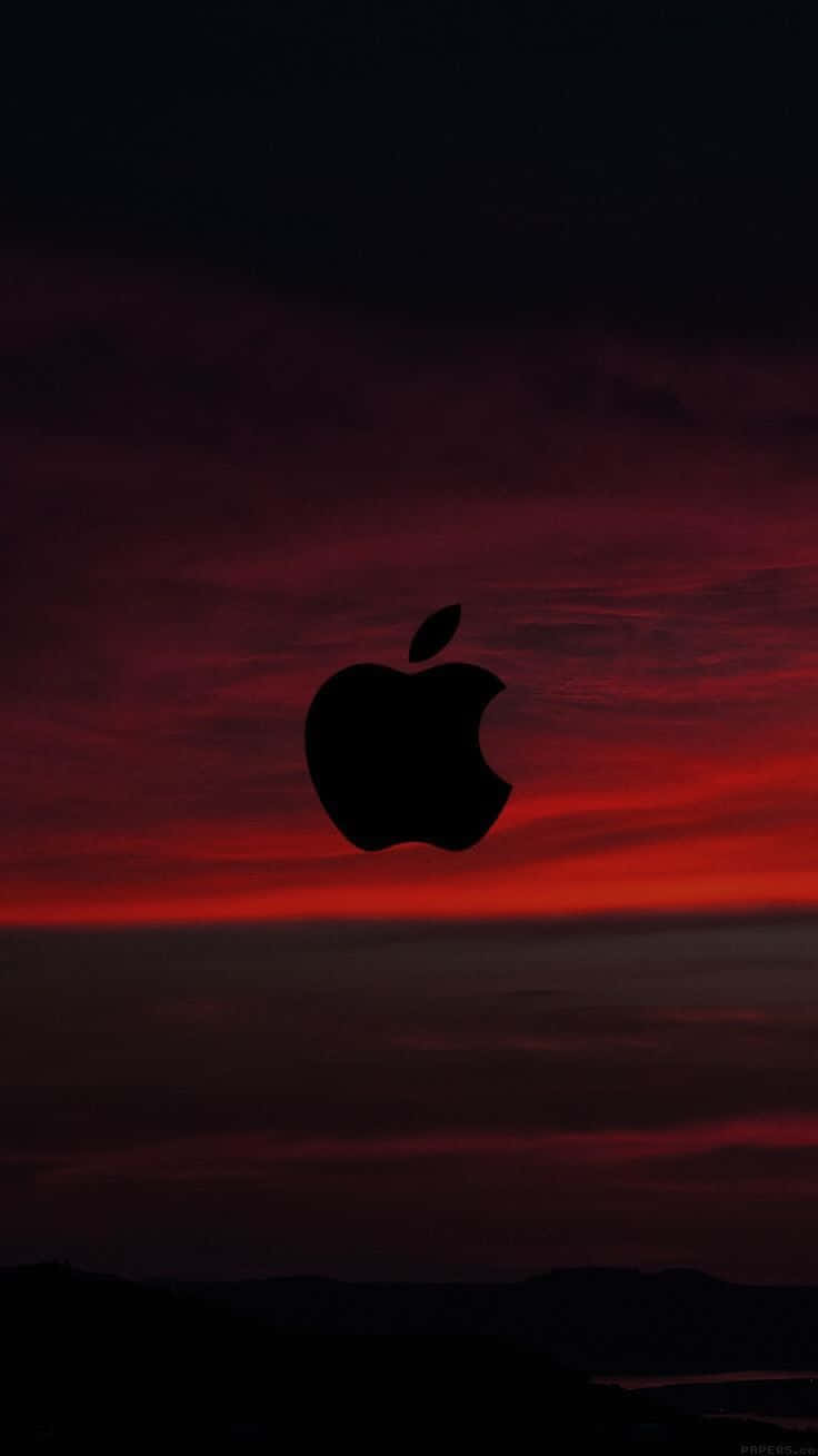 以獨特黑紅 iPhone 提升你的風格 壁紙 — 一個黑色的Apple標誌剪影在遠處山丘上熾熱的紅色和深紫色日落天空中脫穎而出。