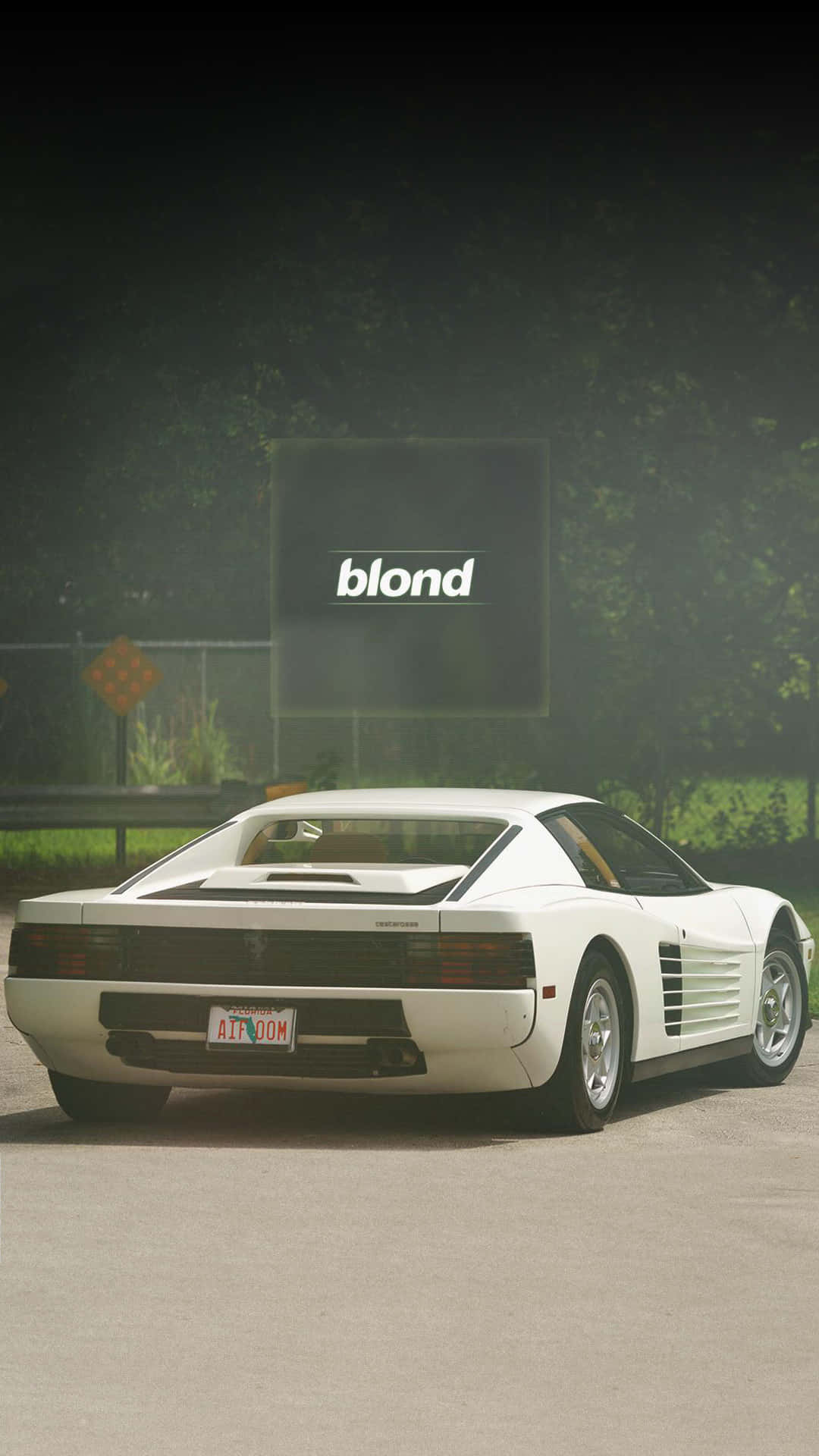 白色法拉利Testarossa在夜間停放在一個發光的「blond」標誌附近。