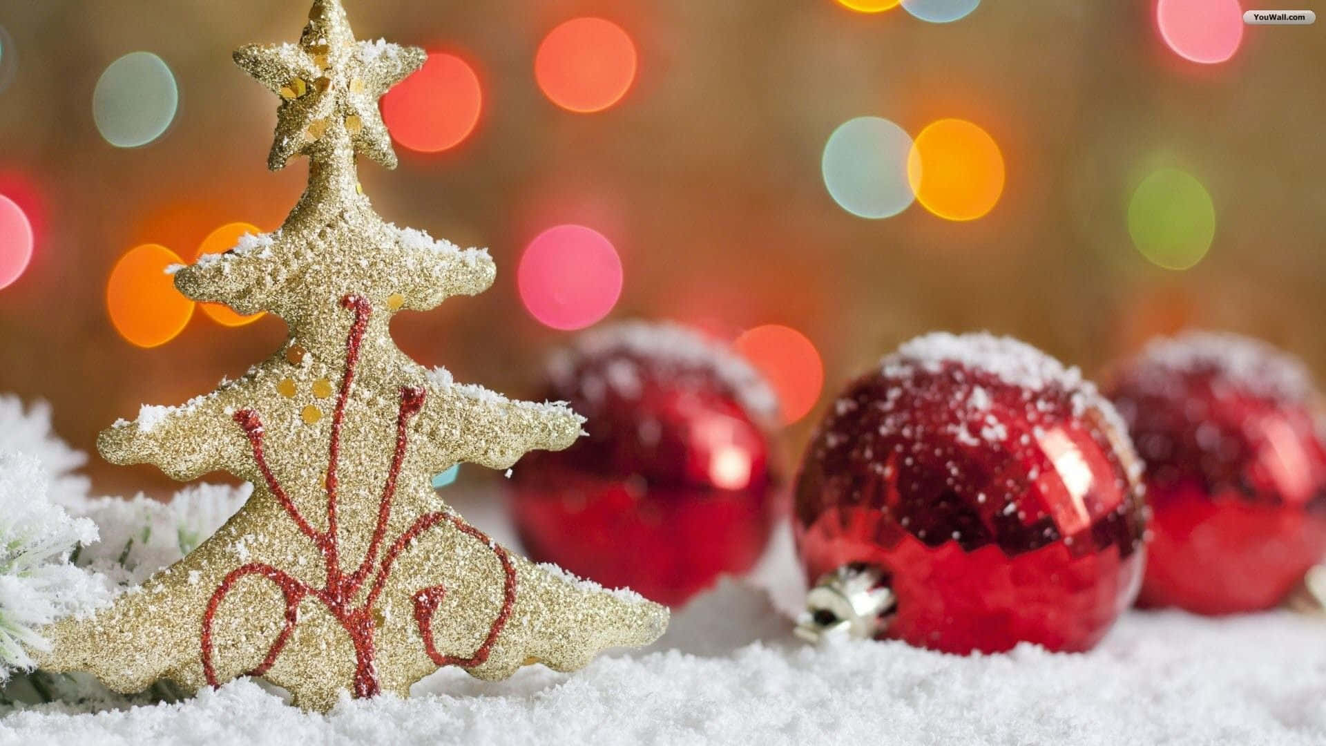 雪中的閃閃發光金色聖誕樹和紅色裝飾，配以節日燈光。
