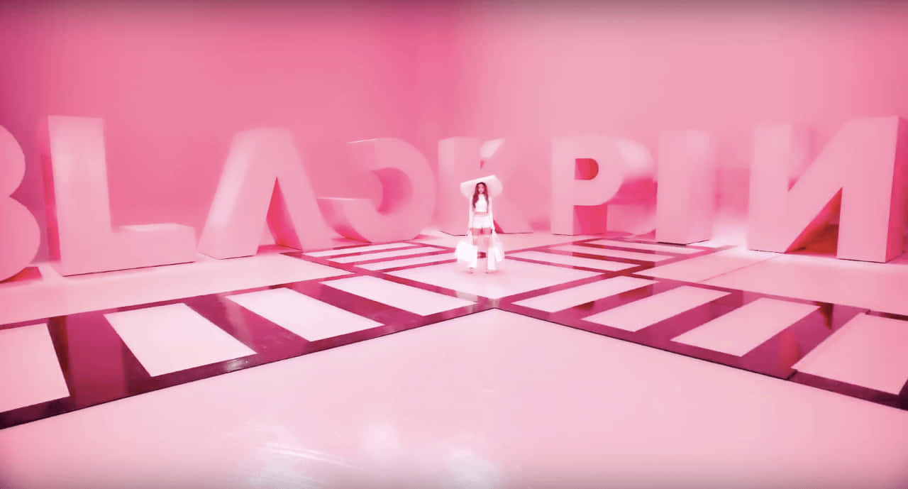 一個表演者喺有巨型BLACKPINK字母同棋盤地板嘅粉紅色房間。