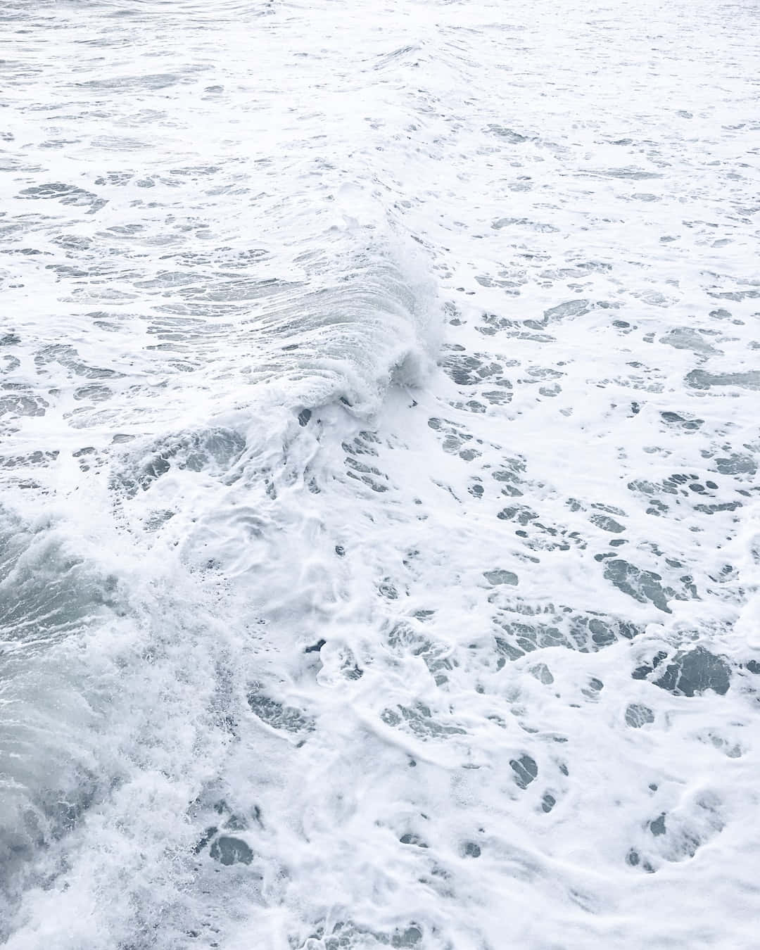 泡沫海浪翻滾，白色浪花與灰藍色海水。