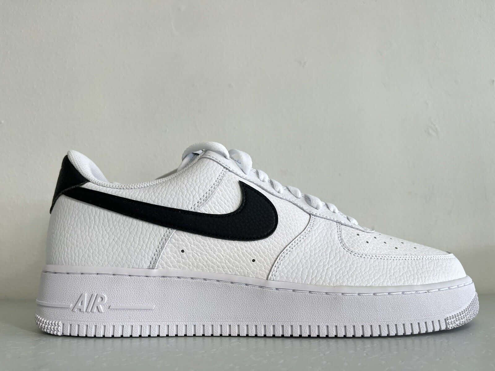 灰色表面上帶有黑色Swoosh的白色Nike Air Force 1運動鞋。
