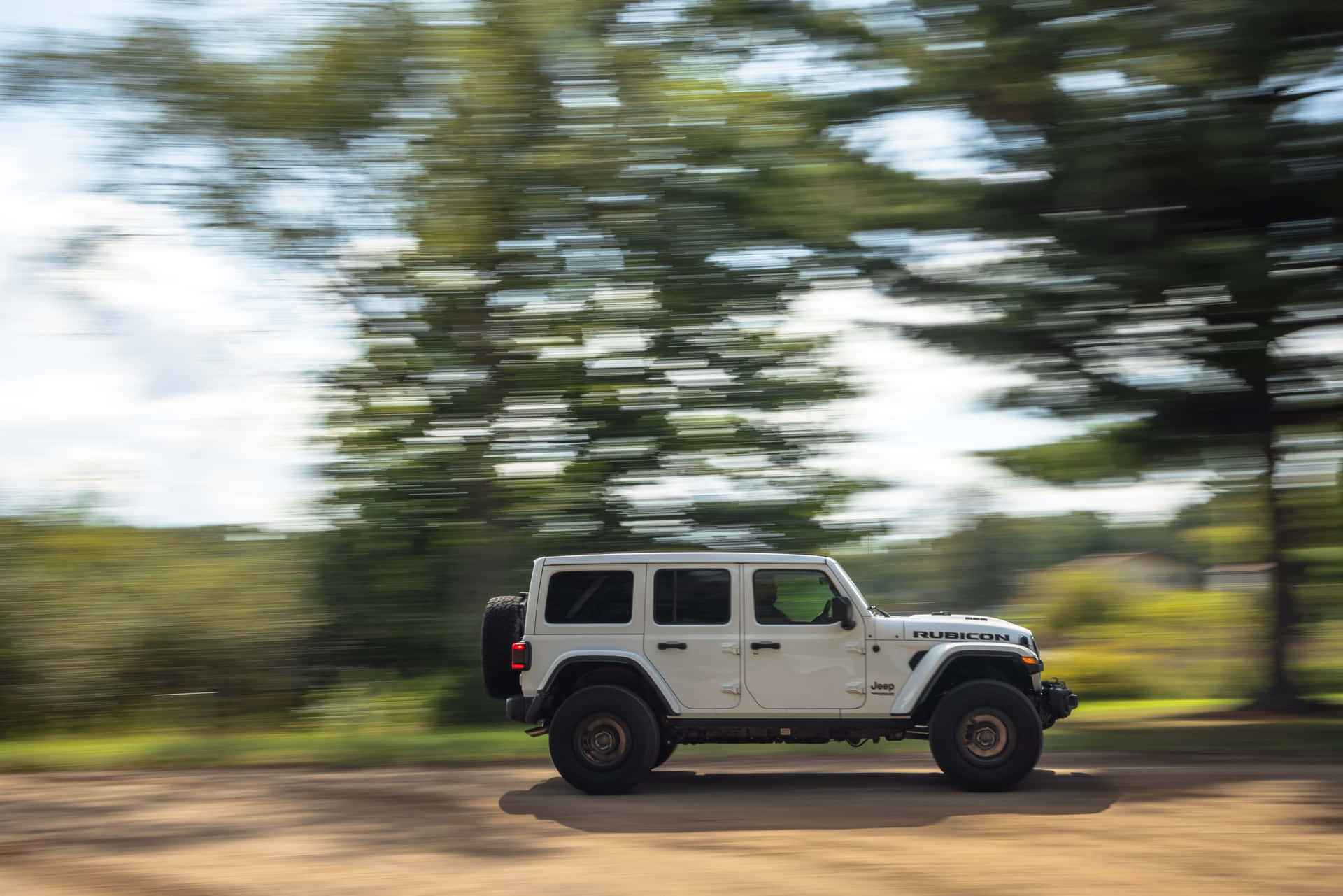 白色Jeep Rubicon在森林地區的泥路上行駛。