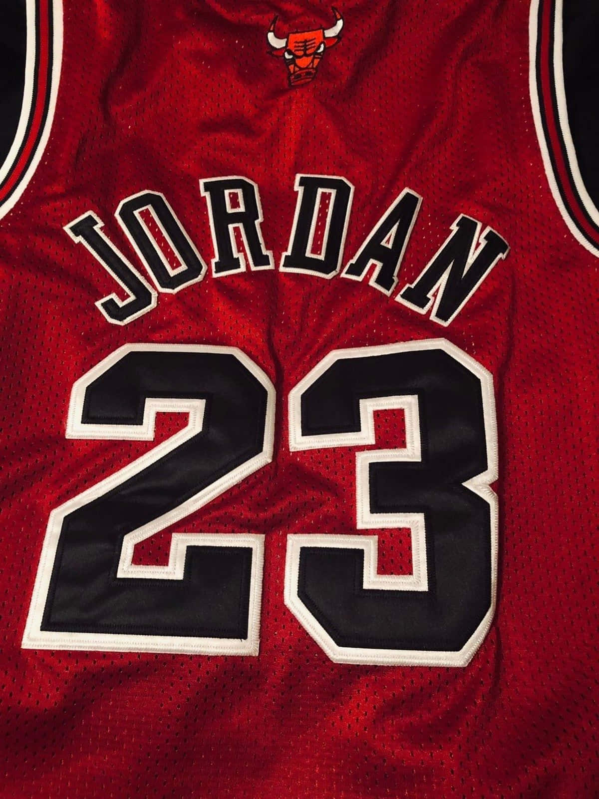 以經典球衣慶祝NBA傳奇邁克爾·喬丹 壁紙 — 芝加哥公牛隊紅色球衣特寫，上面有粗體黑白字樣的 'JORDAN' 和號碼 '23'。